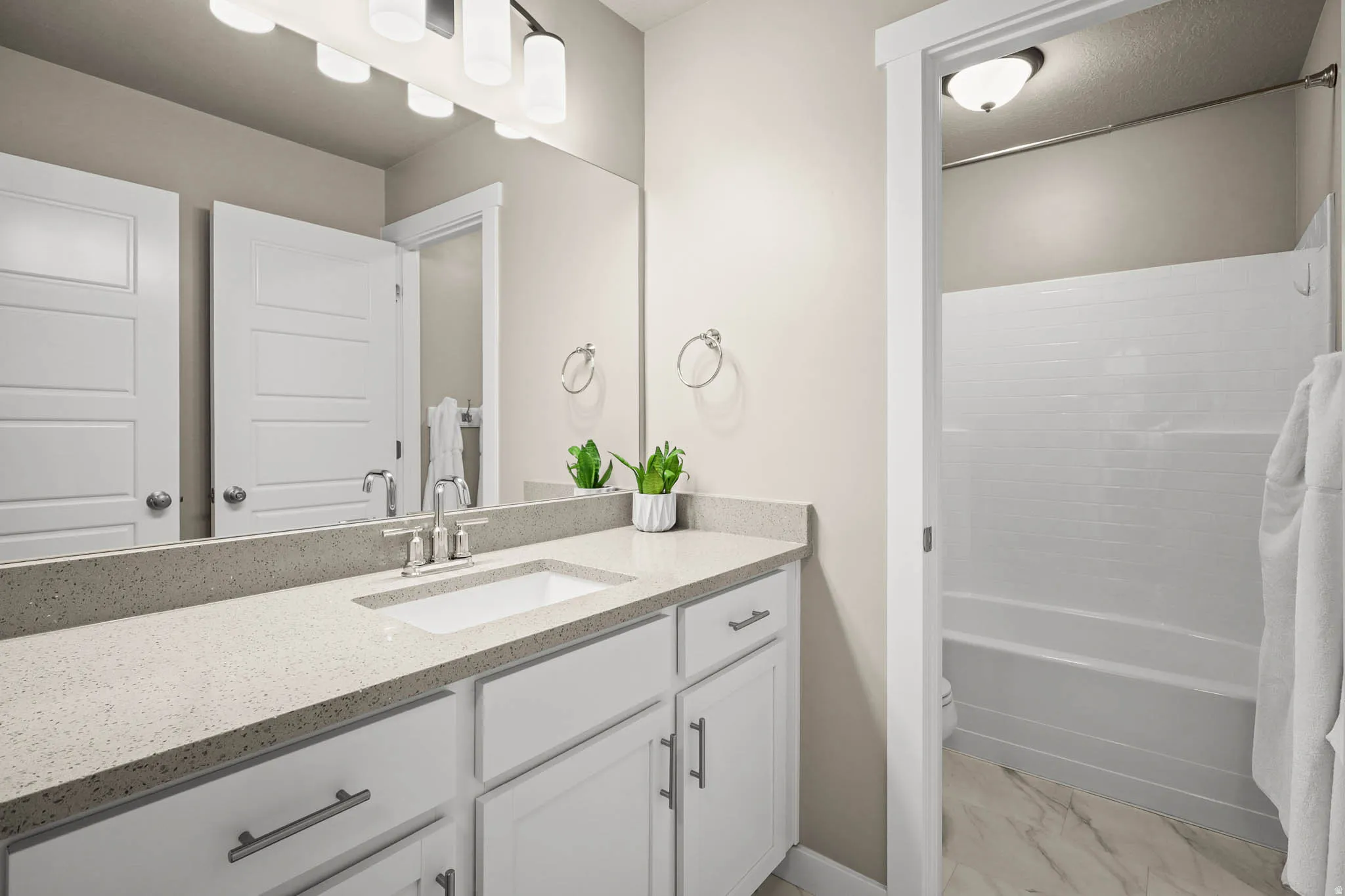 Full bath with vanity, shower / tub combo with curtain, and light marble finish floors