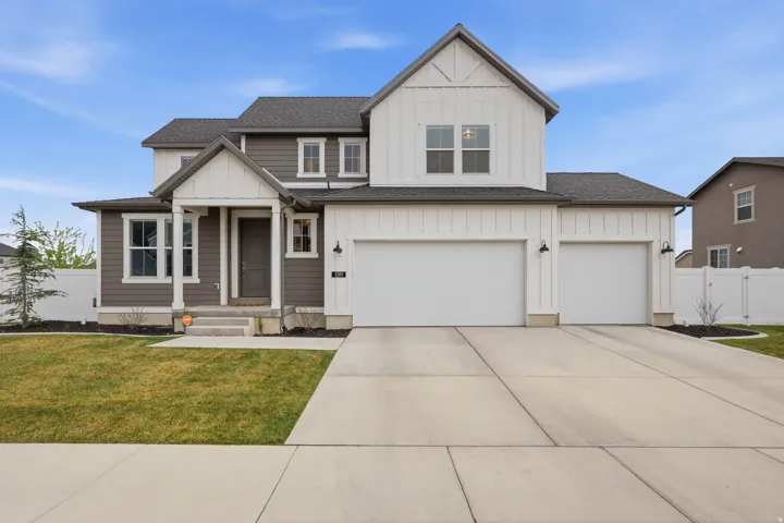 View of front of property featuring board and batten siding, roof with shingles, concrete driveway, and an attached garage