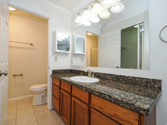 Bathroom with vanity, crown molding, light tile patterned flooring, and an enclosed shower