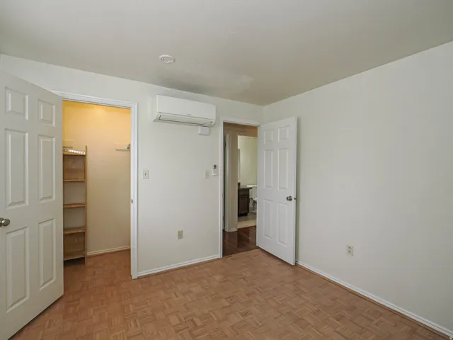 Unfurnished bedroom featuring a walk in closet and parquet floors