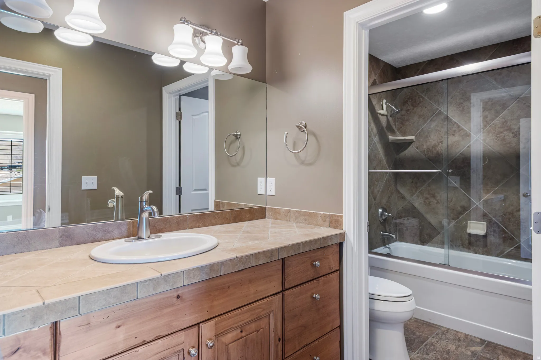 Full bath featuring vanity and bath / shower combo with glass door