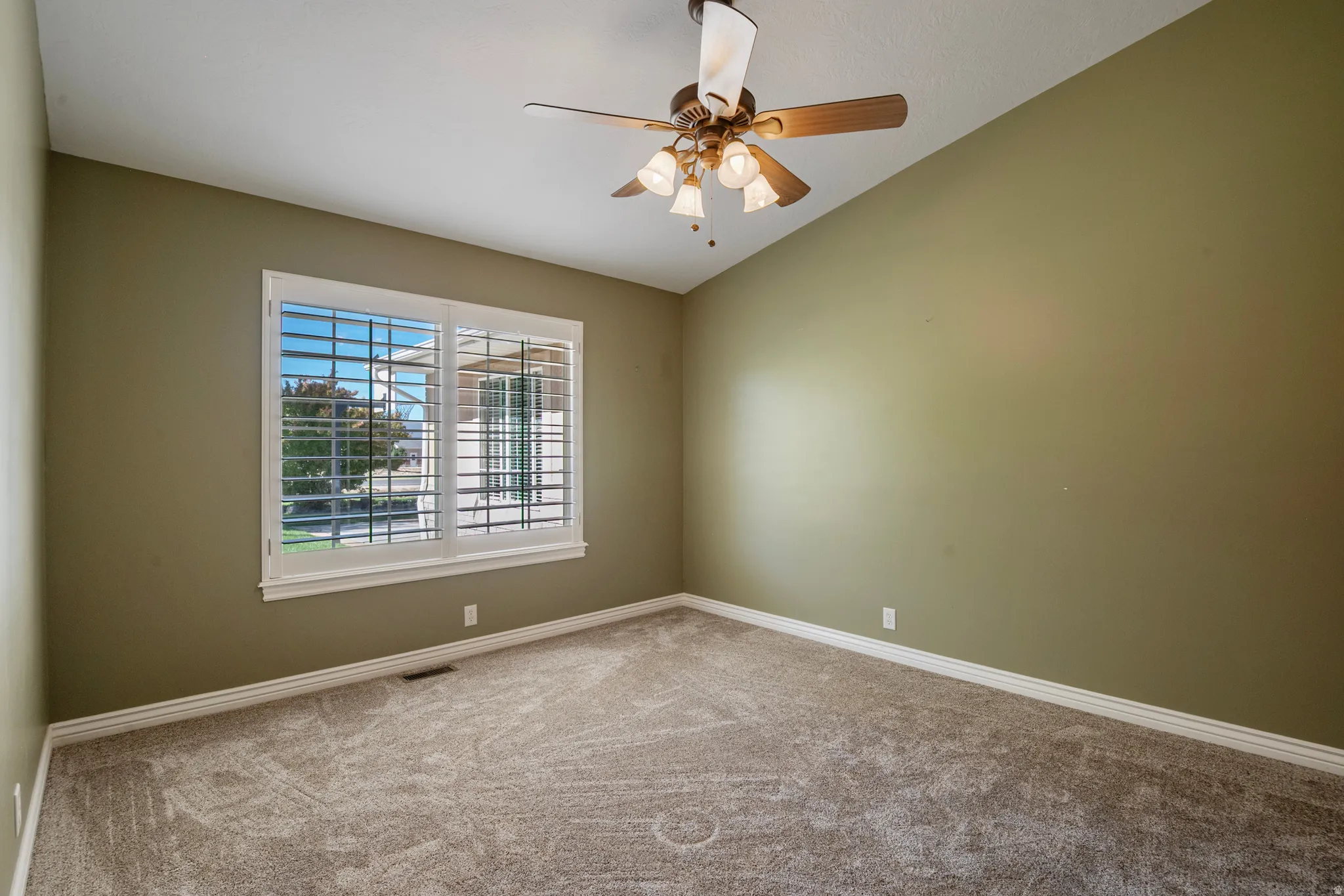 Unfurnished room with lofted ceiling, a ceiling fan, and light carpet
