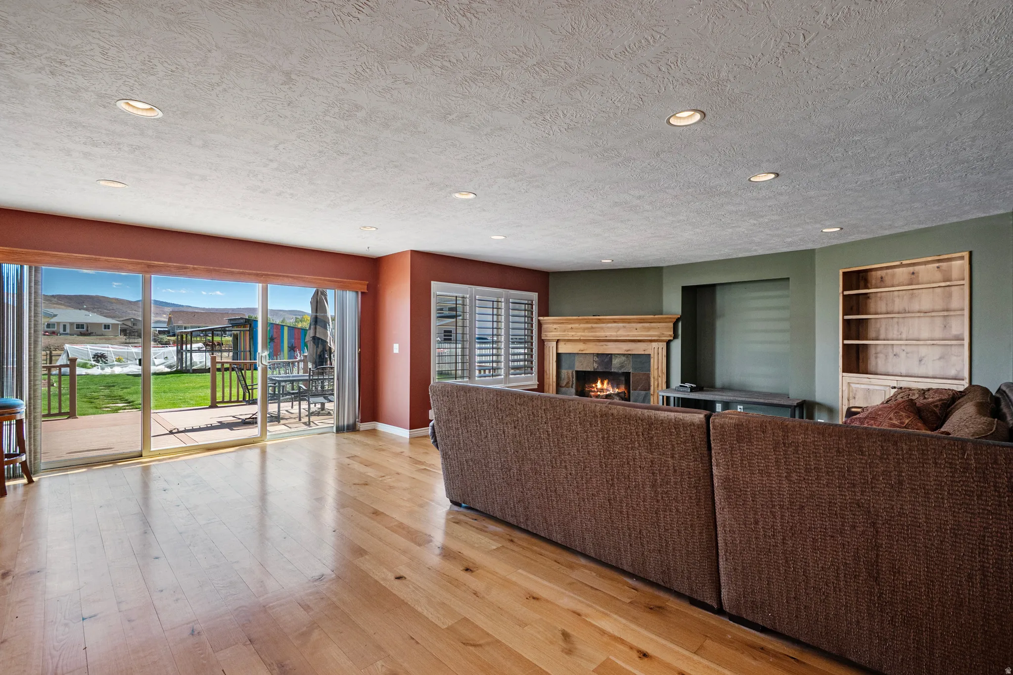 Living room featuring light wood-style flooring, a textured ceiling, a tile fireplace, and recessed lighting