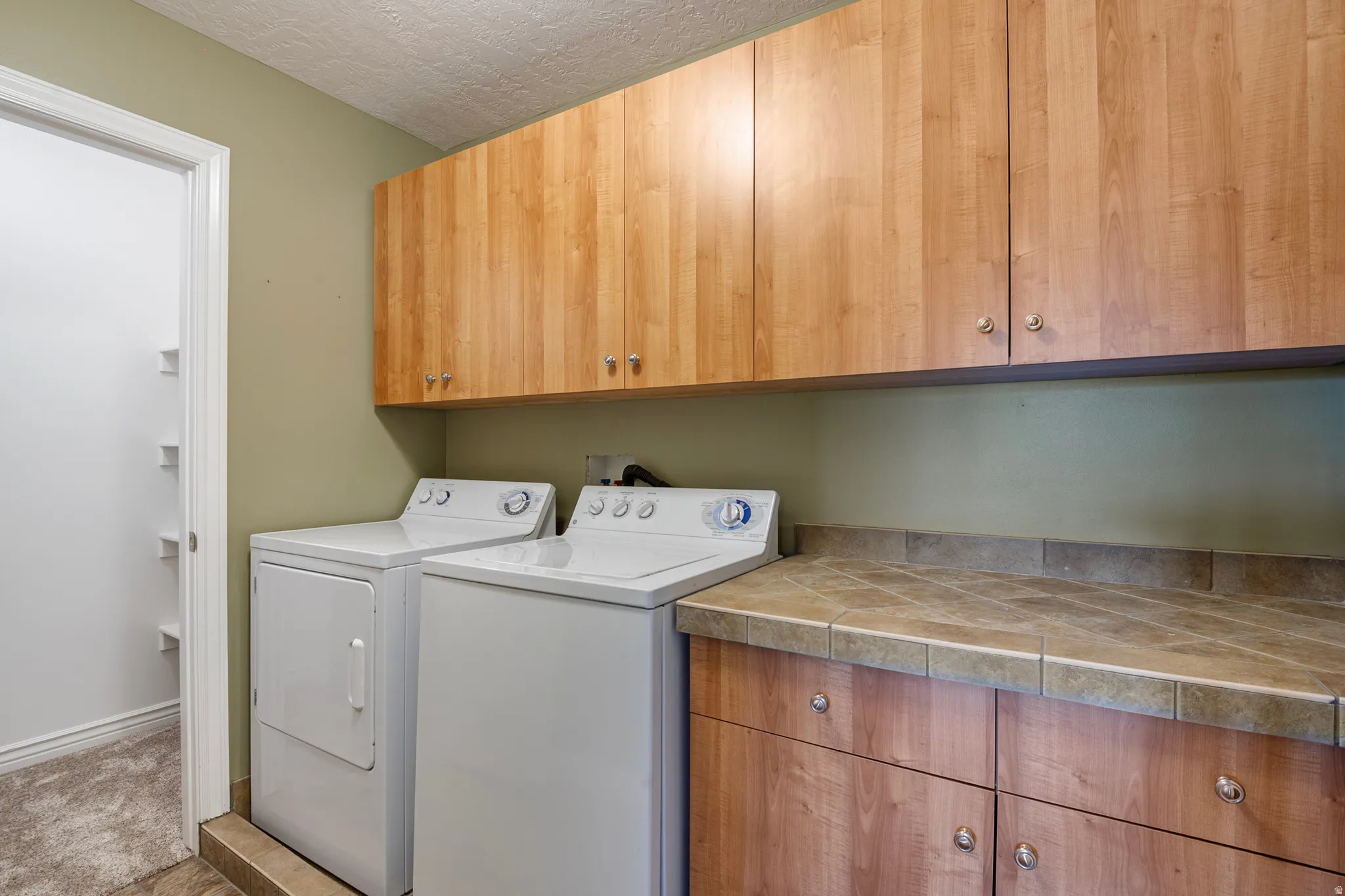 Laundry room with cabinet space, a textured ceiling, and independent washer and dryer