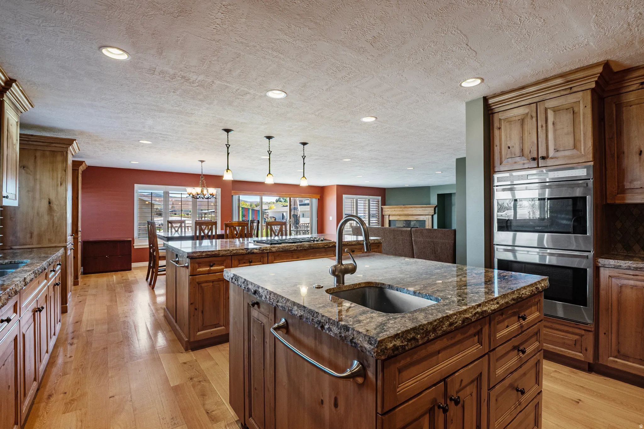 Kitchen with double oven, dark stone countertops, tasteful backsplash, light wood finished floors, and plenty of natural light