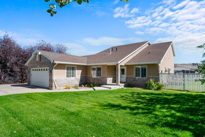 Ranch-style home featuring stucco siding, a garage, driveway, and stone siding