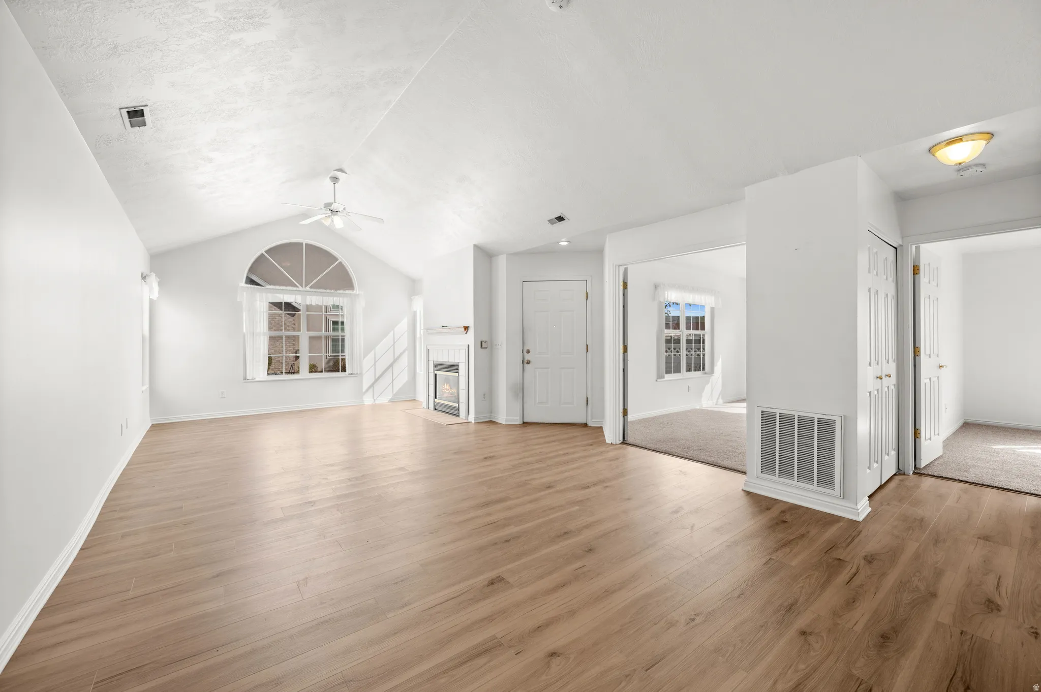 Unfurnished living room with a fireplace, light wood-style floors, and ceiling fan