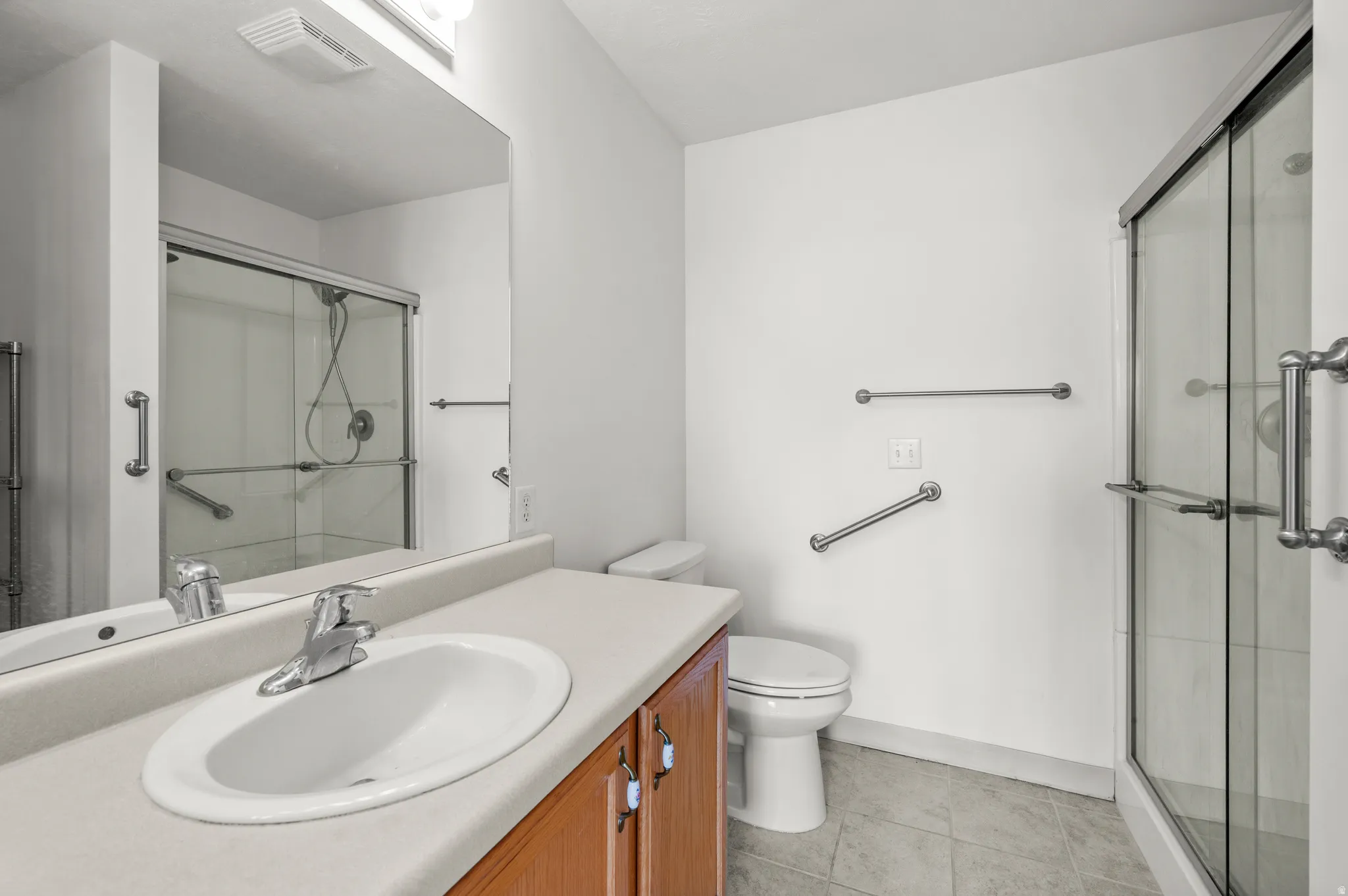 Full bath featuring vanity, a shower stall, and light tile patterned floors