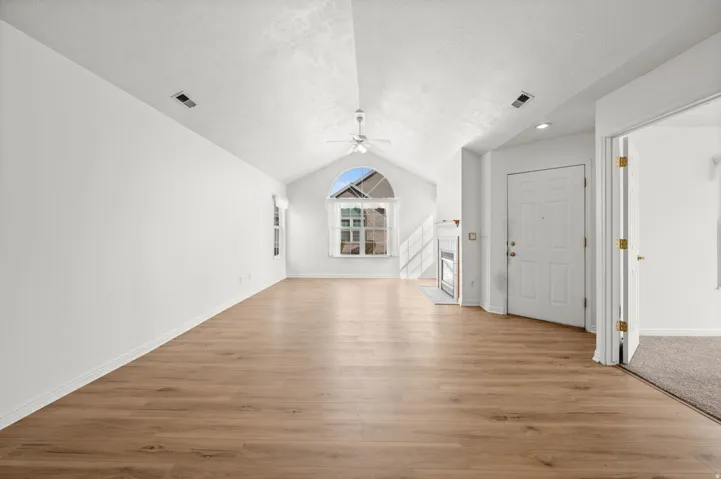 Additional living space featuring a ceiling fan, light wood-type flooring, a tiled fireplace, and a textured ceiling