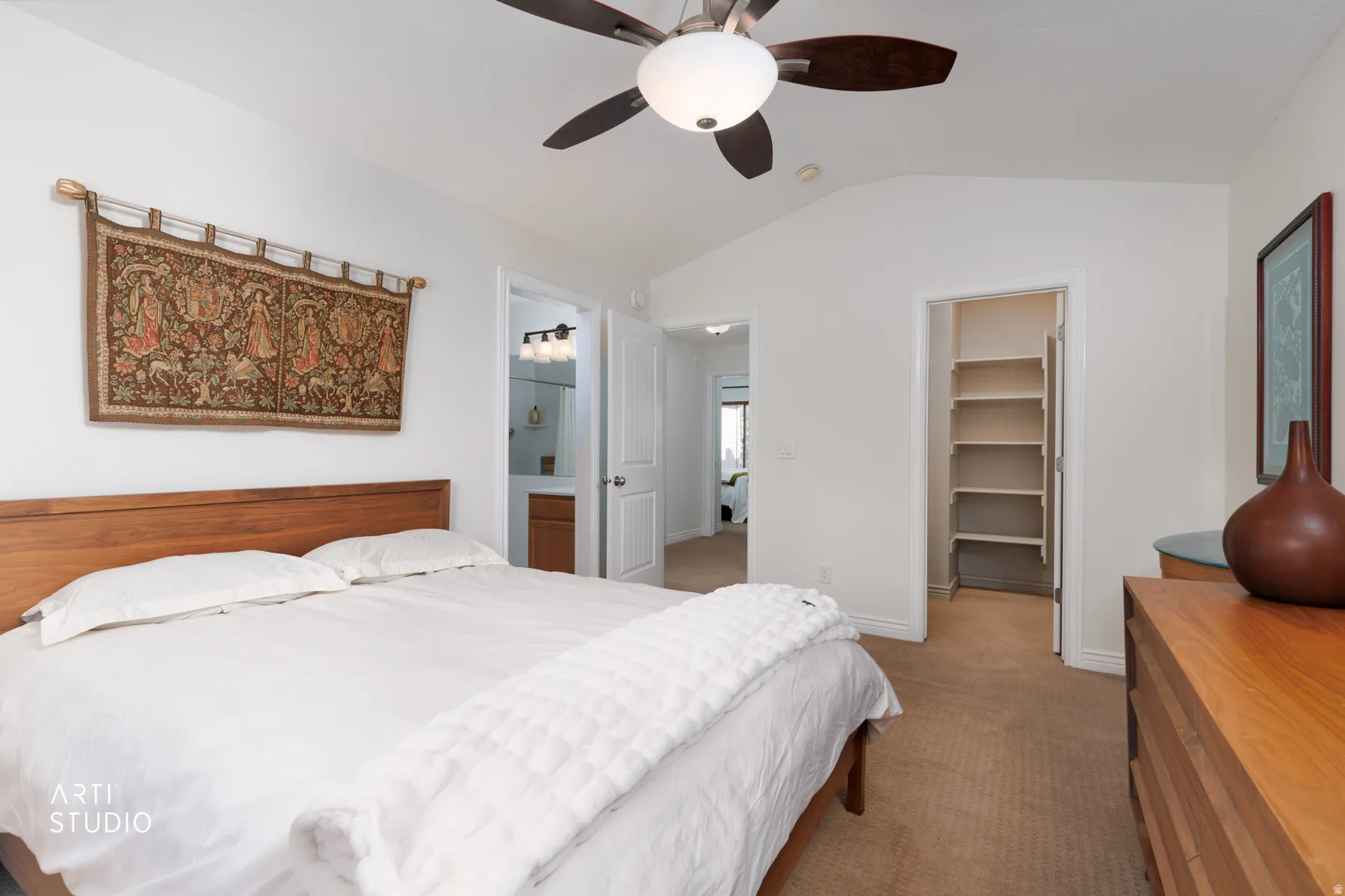Carpeted bedroom with vaulted ceiling, a walk in closet, a ceiling fan, and connected bathroom