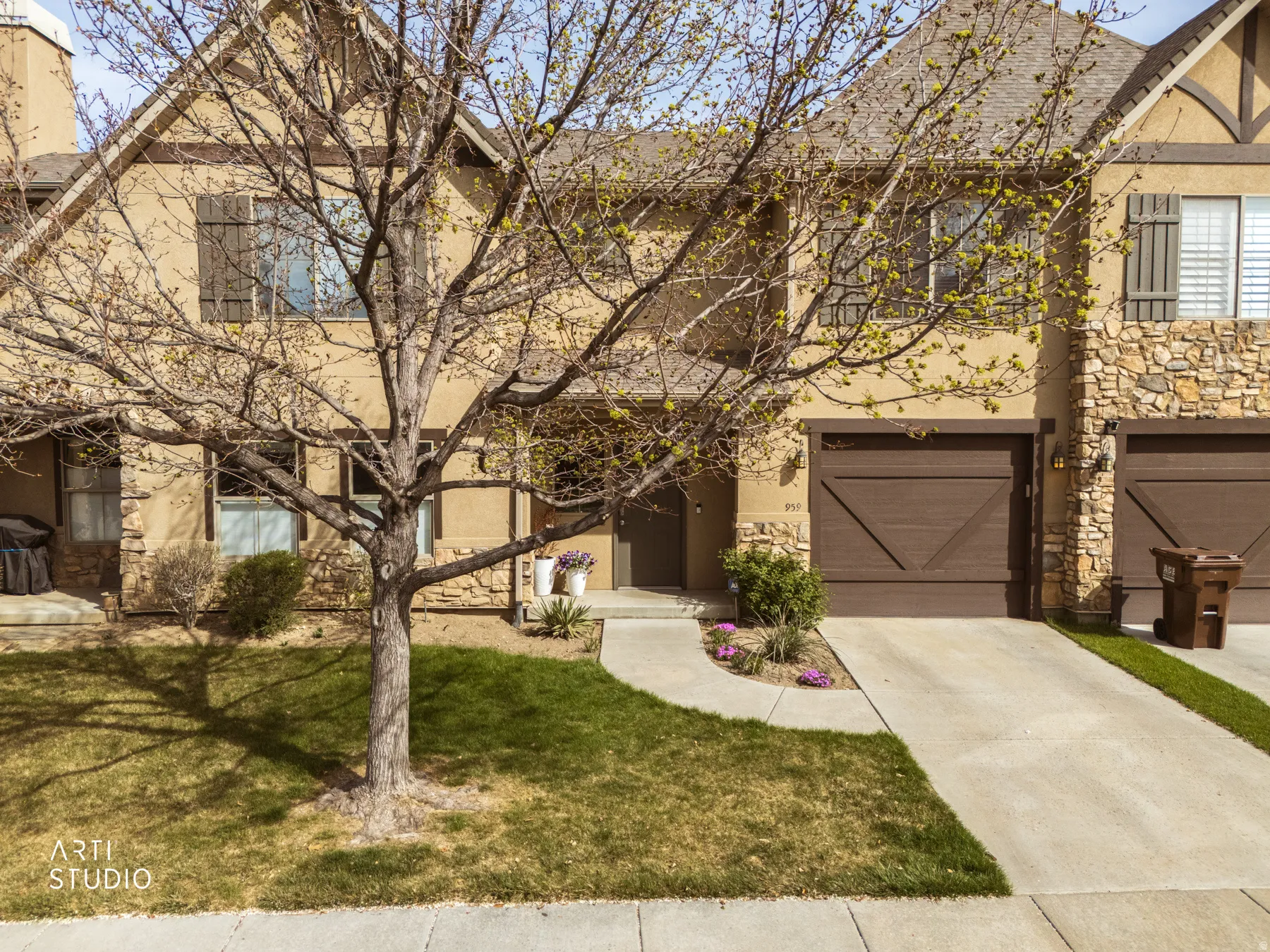 View of front of home with stone siding, stucco siding, a front yard, and an attached garage