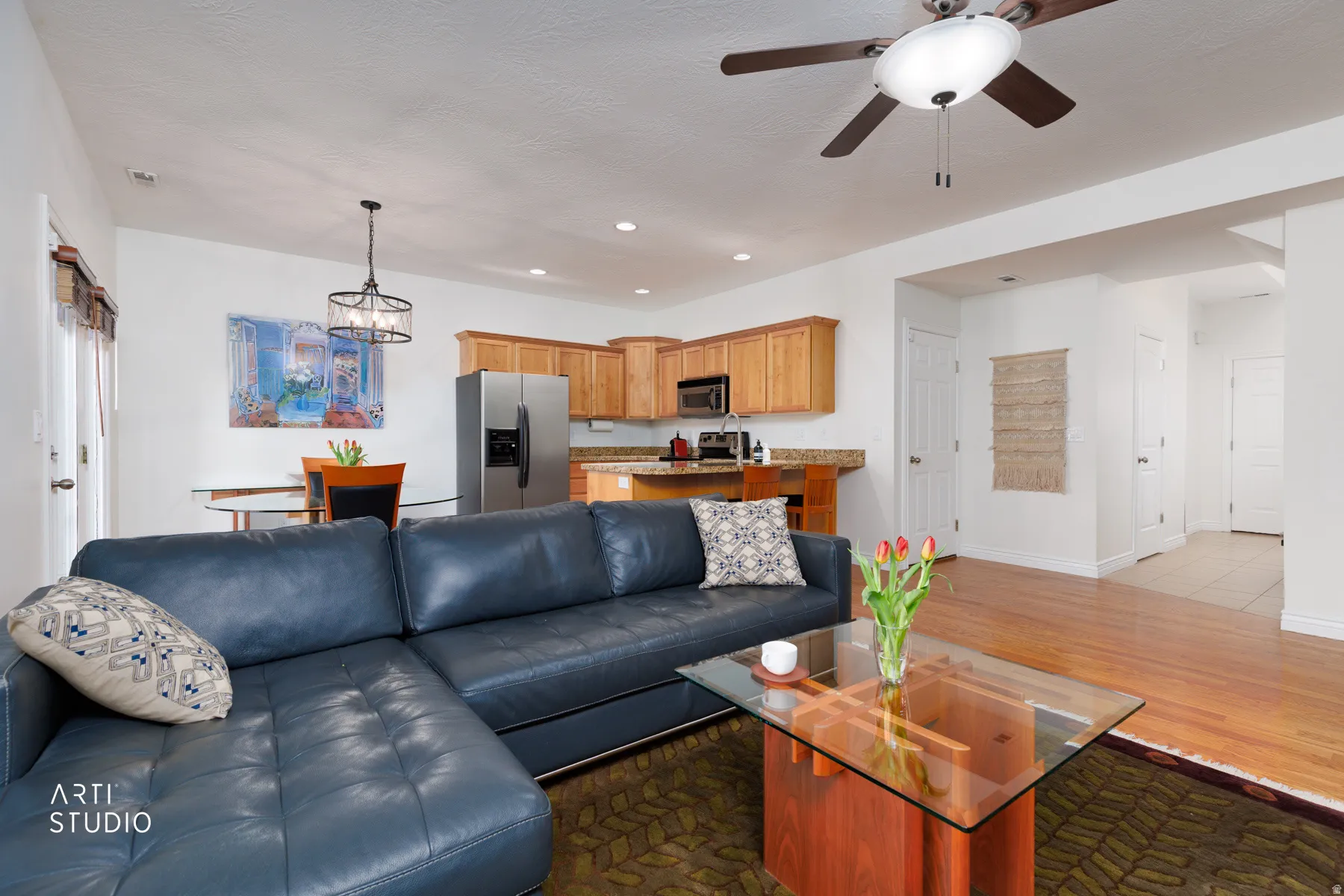 Living room with dark wood finished floors, ceiling fan, and a chandelier