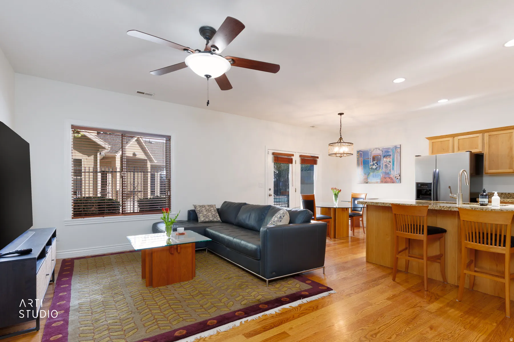 Living room with light wood finished floors, a ceiling fan, and hanging lights