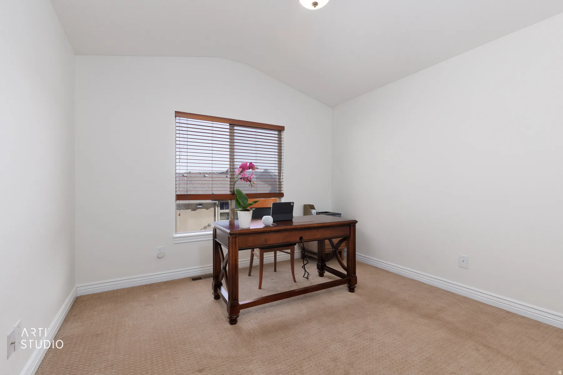 Office area with light carpet and vaulted ceiling