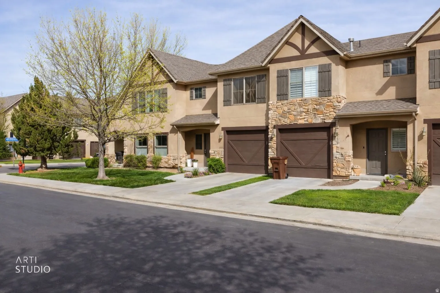 View of front facade featuring stucco siding, stone siding, an attached garage, concrete driveway, and a front lawn