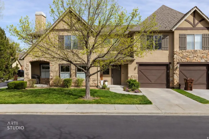 Tudor home featuring stone siding, stucco siding, an attached garage, and a chimney