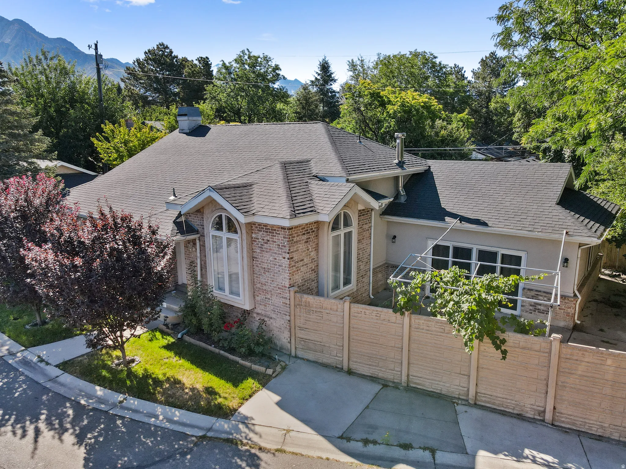 View of front of home featuring a fenced front yard, brick siding, stucco siding, and a shingled roof