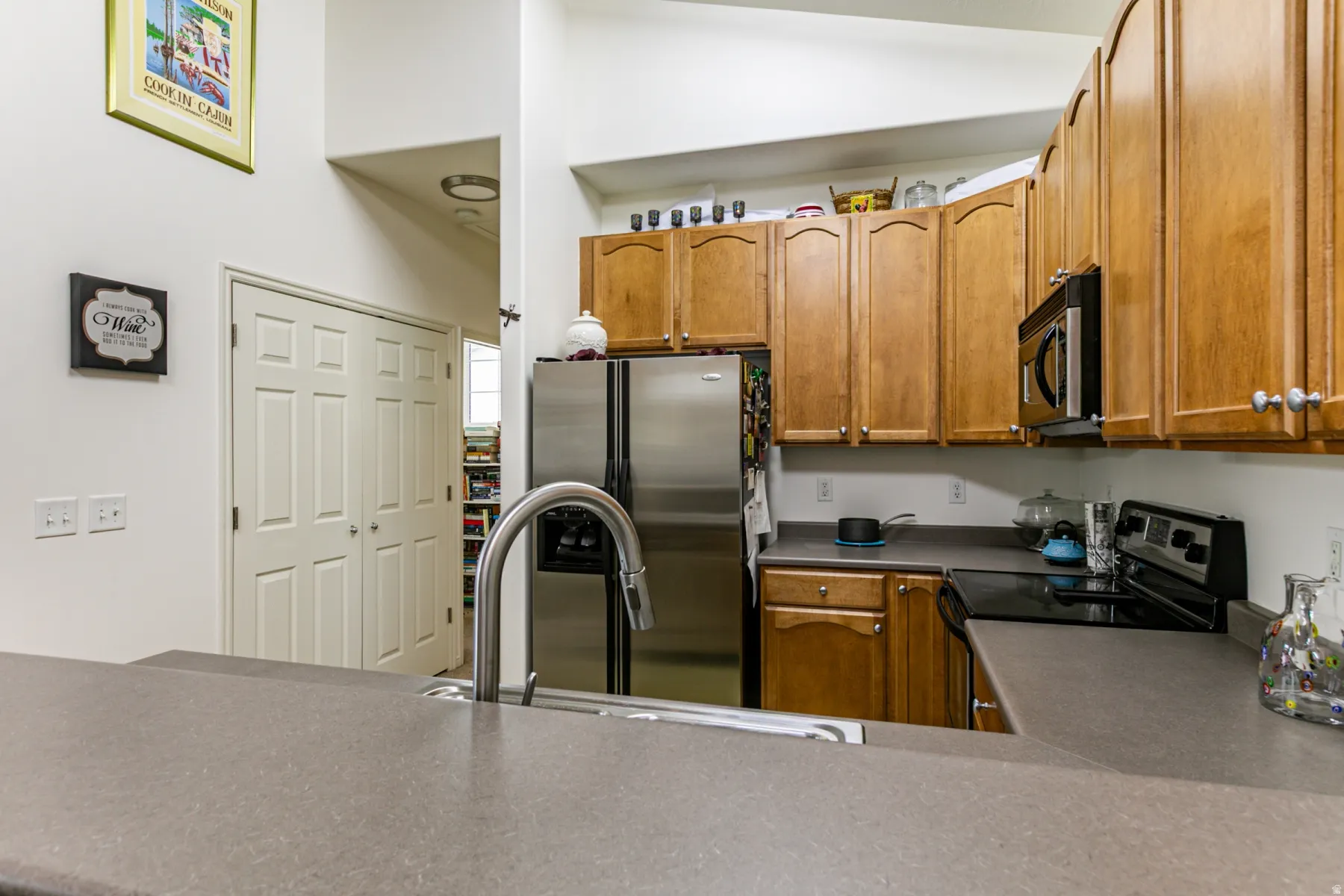 Kitchen with stainless steel appliances, wood finish cabinets, and light countertops