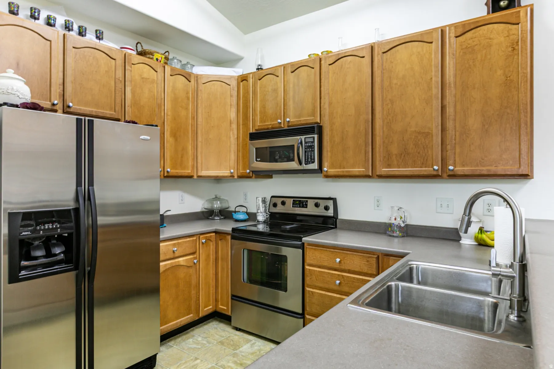 Kitchen with stainless steel appliances, wood finish cabinets, and light countertops
