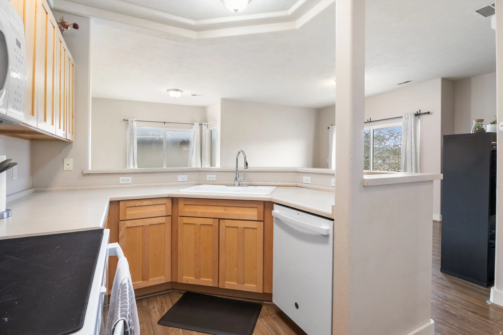 Kitchen with light countertops, white appliances, dark wood-style flooring, and a peninsula
