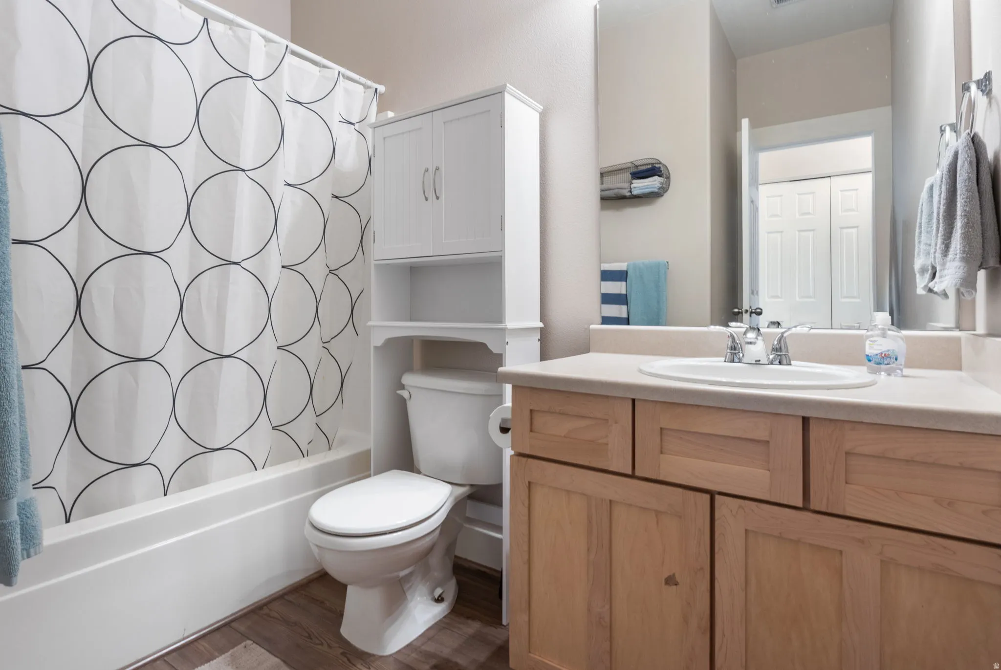 Full bathroom featuring vanity, shower / bath combo with shower curtain, and dark wood-style flooring