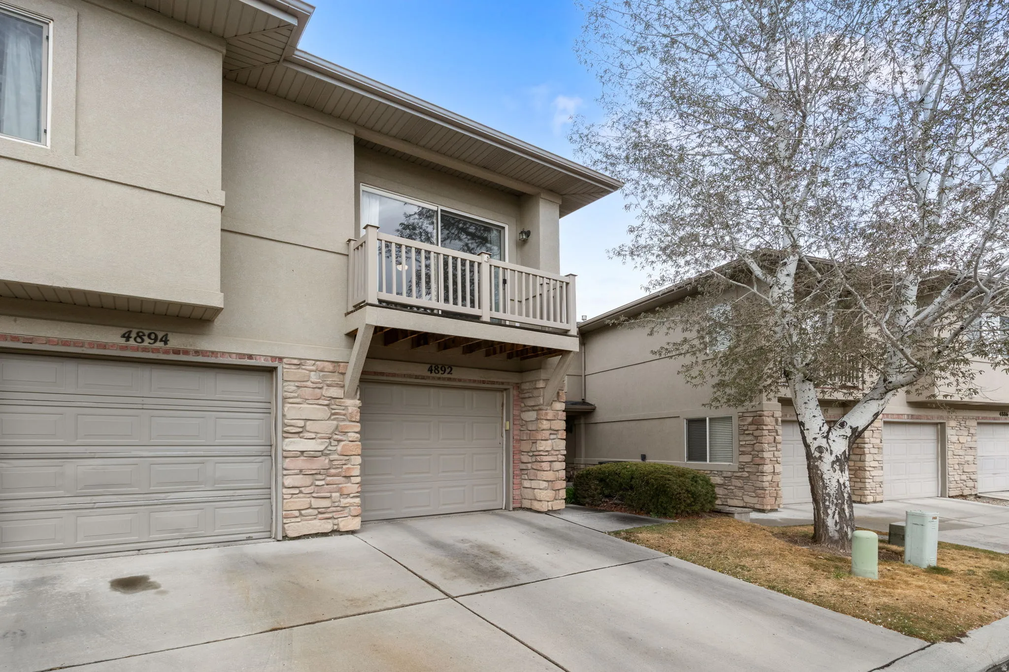 Traditional-style house with a balcony, stone siding, stucco siding, and a garage