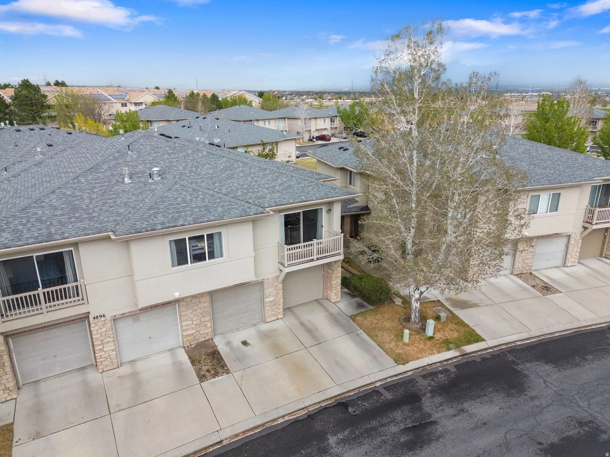 Traditional-style home featuring stucco siding, a shingled roof, an attached garage, a balcony, and driveway