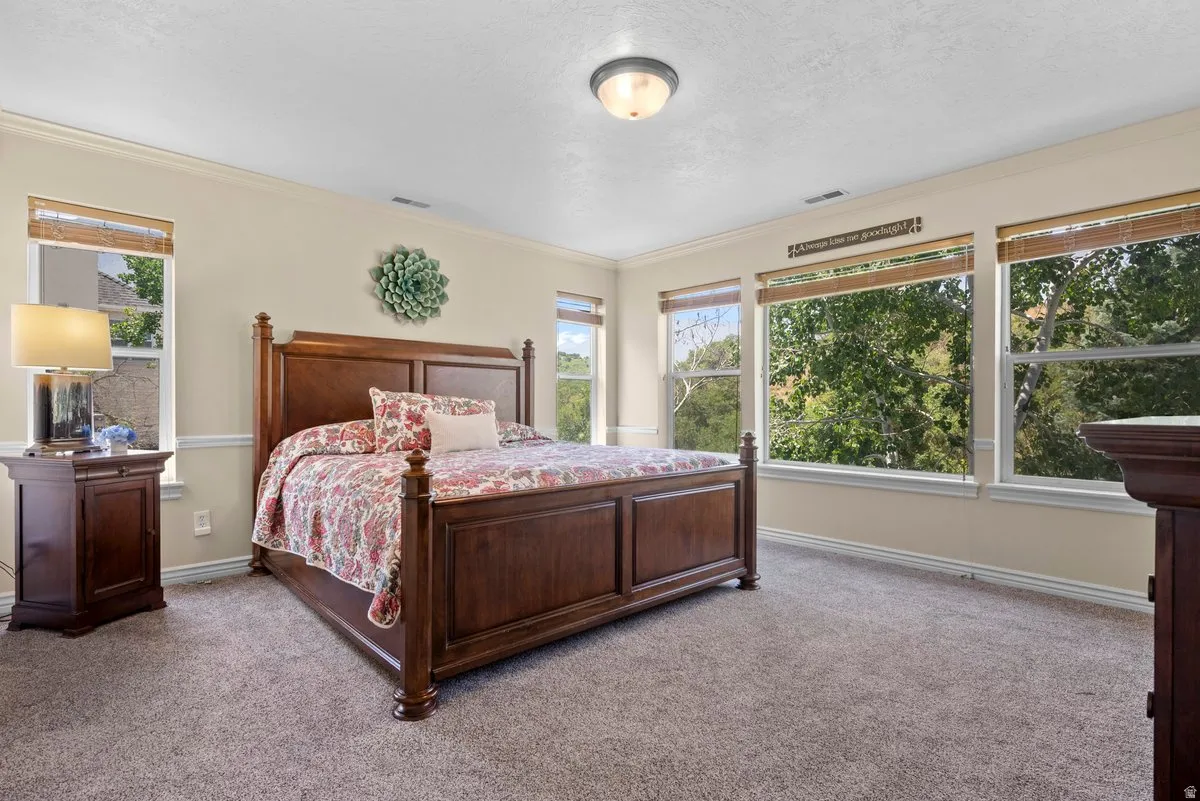 Carpeted bedroom featuring ornamental molding and a textured ceiling