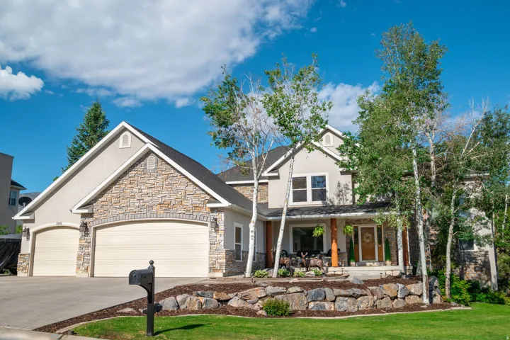 Craftsman-style home with an attached garage, stone siding, driveway, stucco siding, and a large covered porch