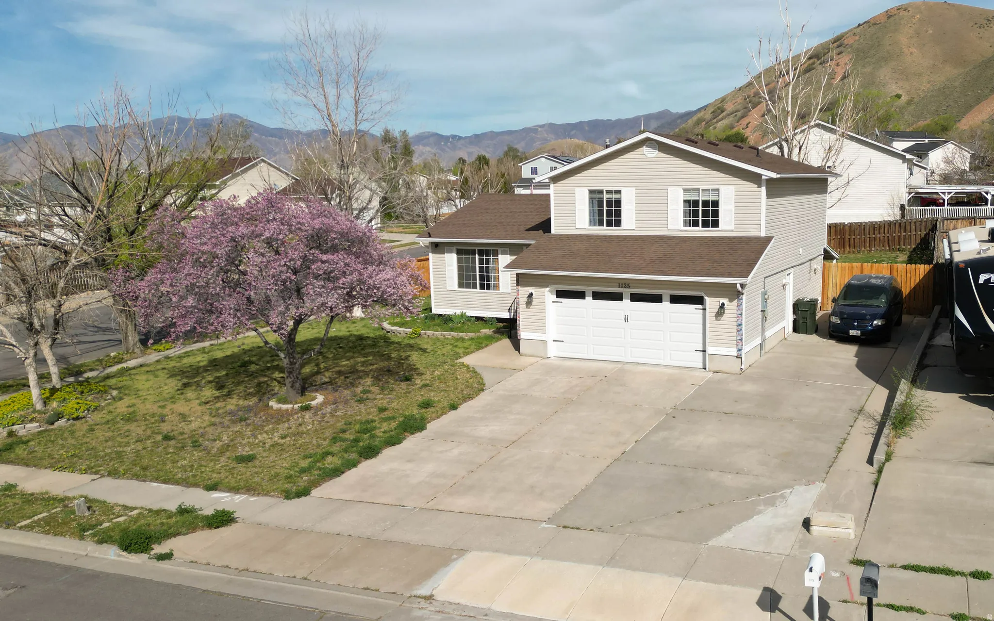 View of front facade with an attached garage, driveway, a mountain view, and a shingled roof