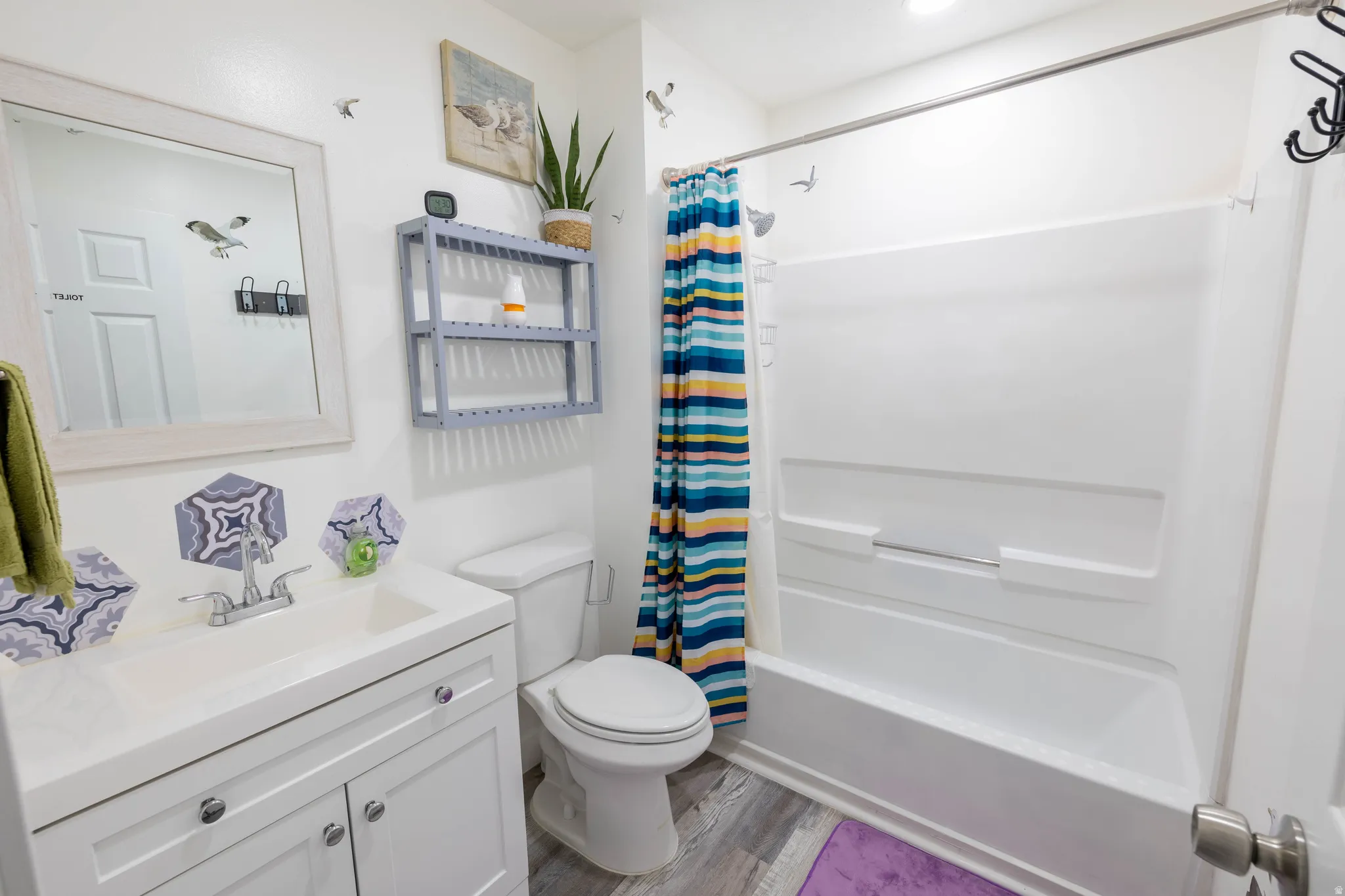 Bathroom featuring vanity, shower / bath combo with shower curtain, and light wood-style floors