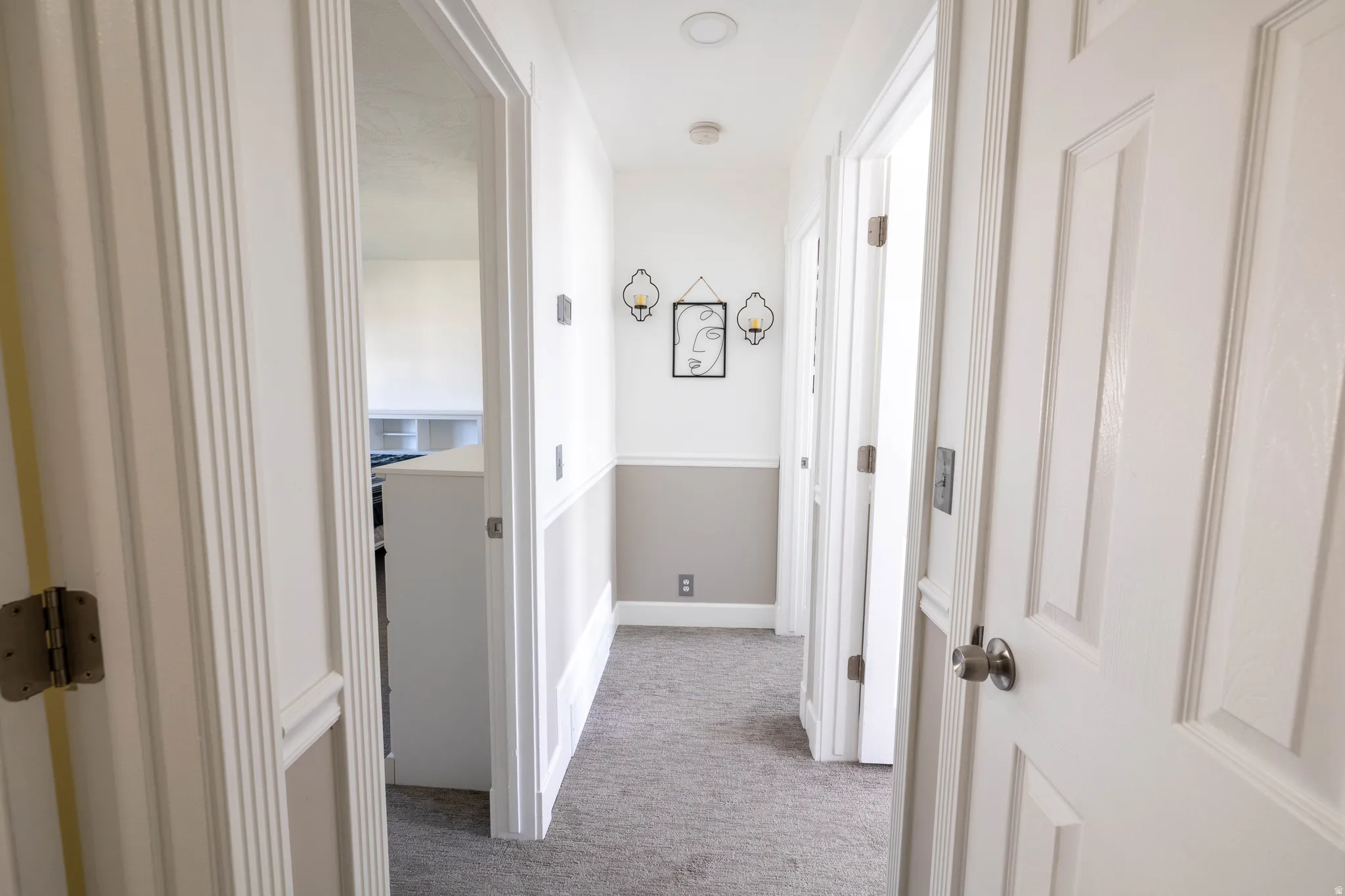 Hallway featuring light colored carpet and baseboards