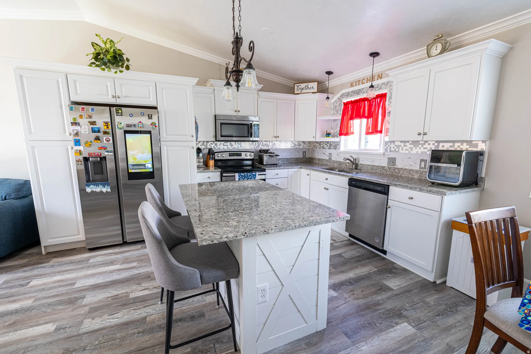 Kitchen with stainless steel appliances, white cabinetry, a kitchen bar, light stone countertops, and a center island