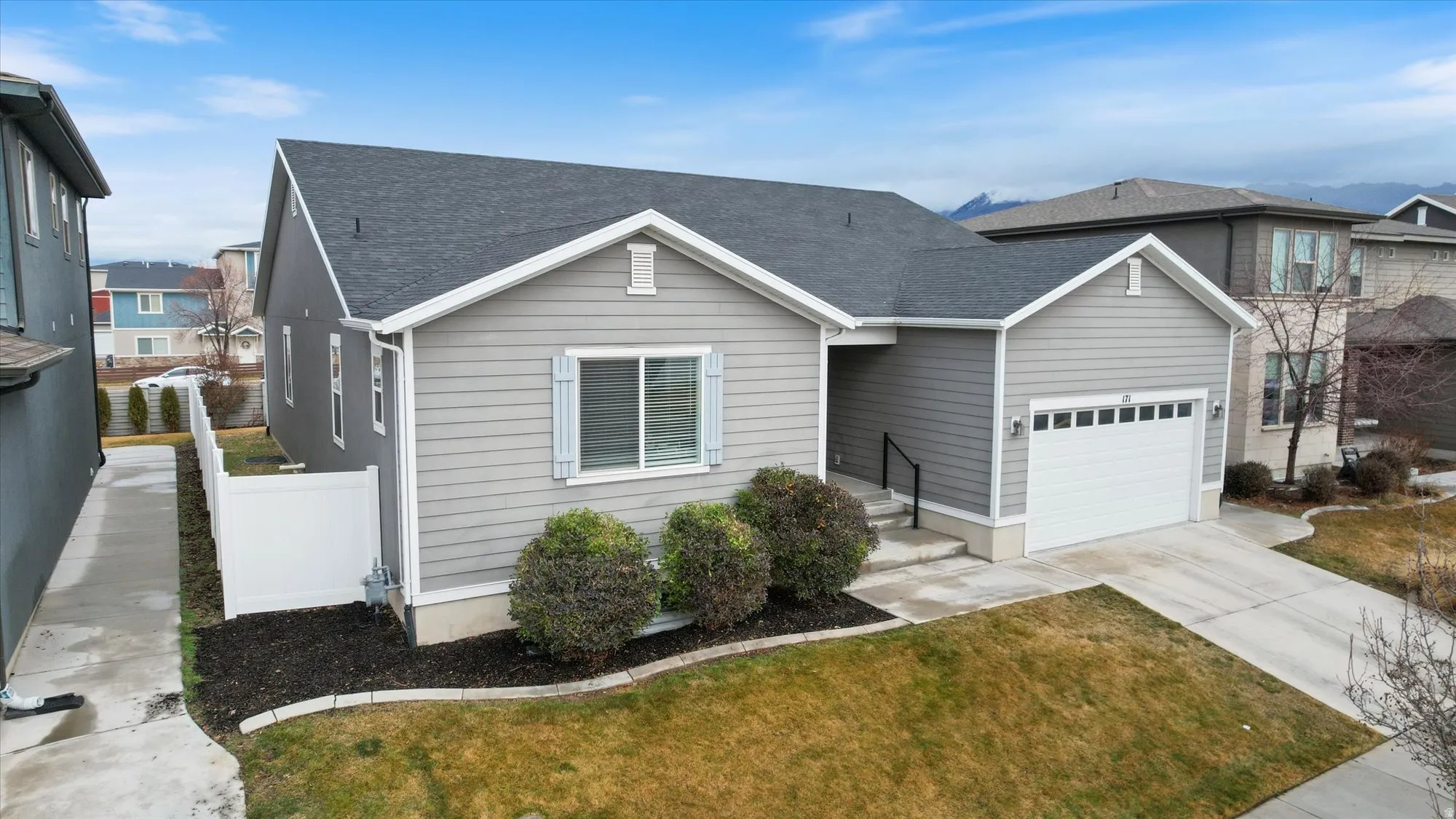 View of front facade featuring roof with shingles, driveway, and an attached garage