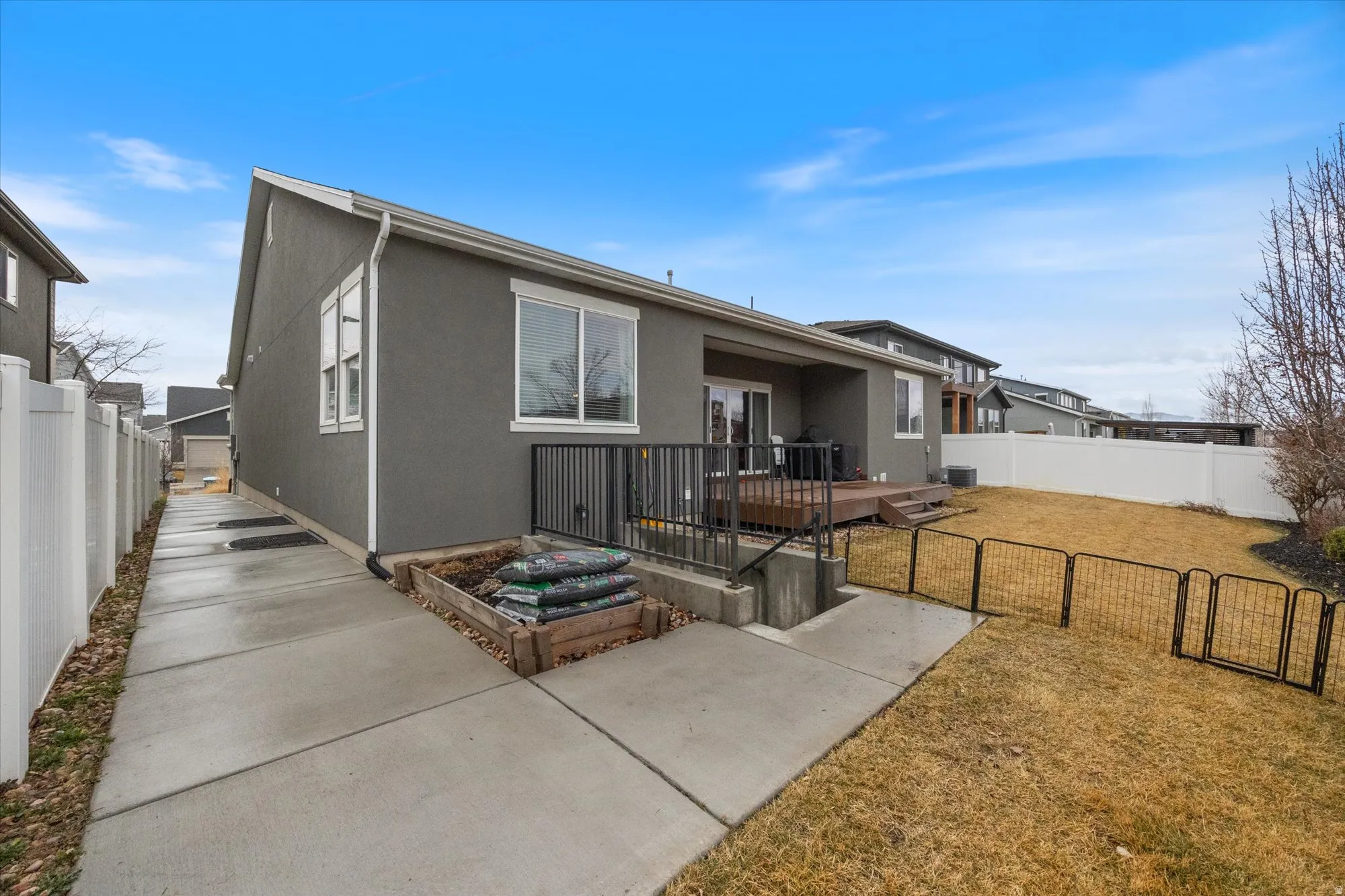 Back of house featuring a gate, a fenced backyard, stucco siding, and a deck