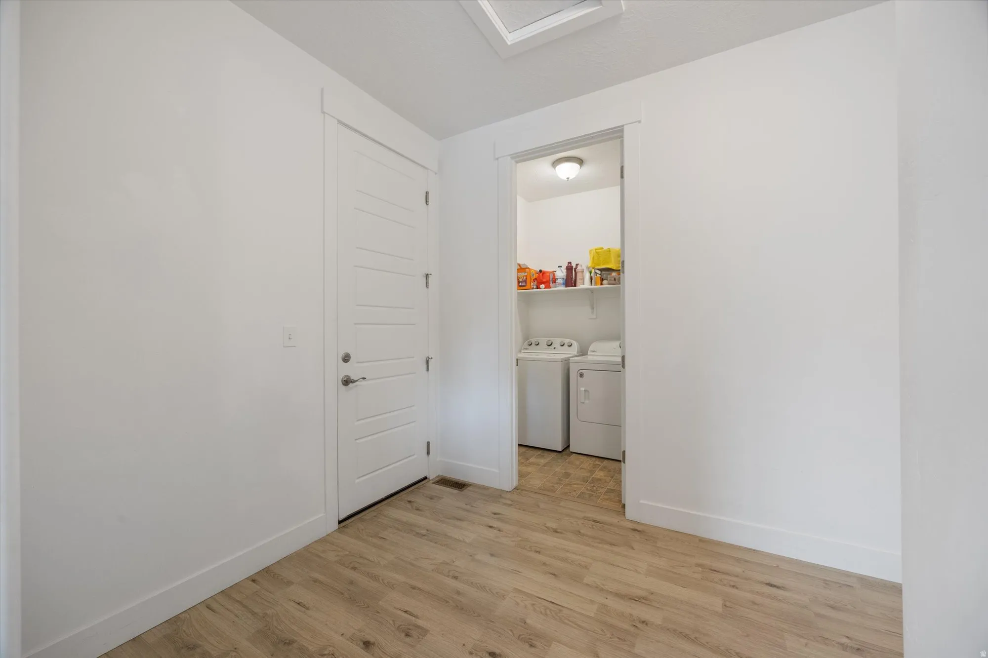 Laundry area featuring light wood finished floors and washer and dryer