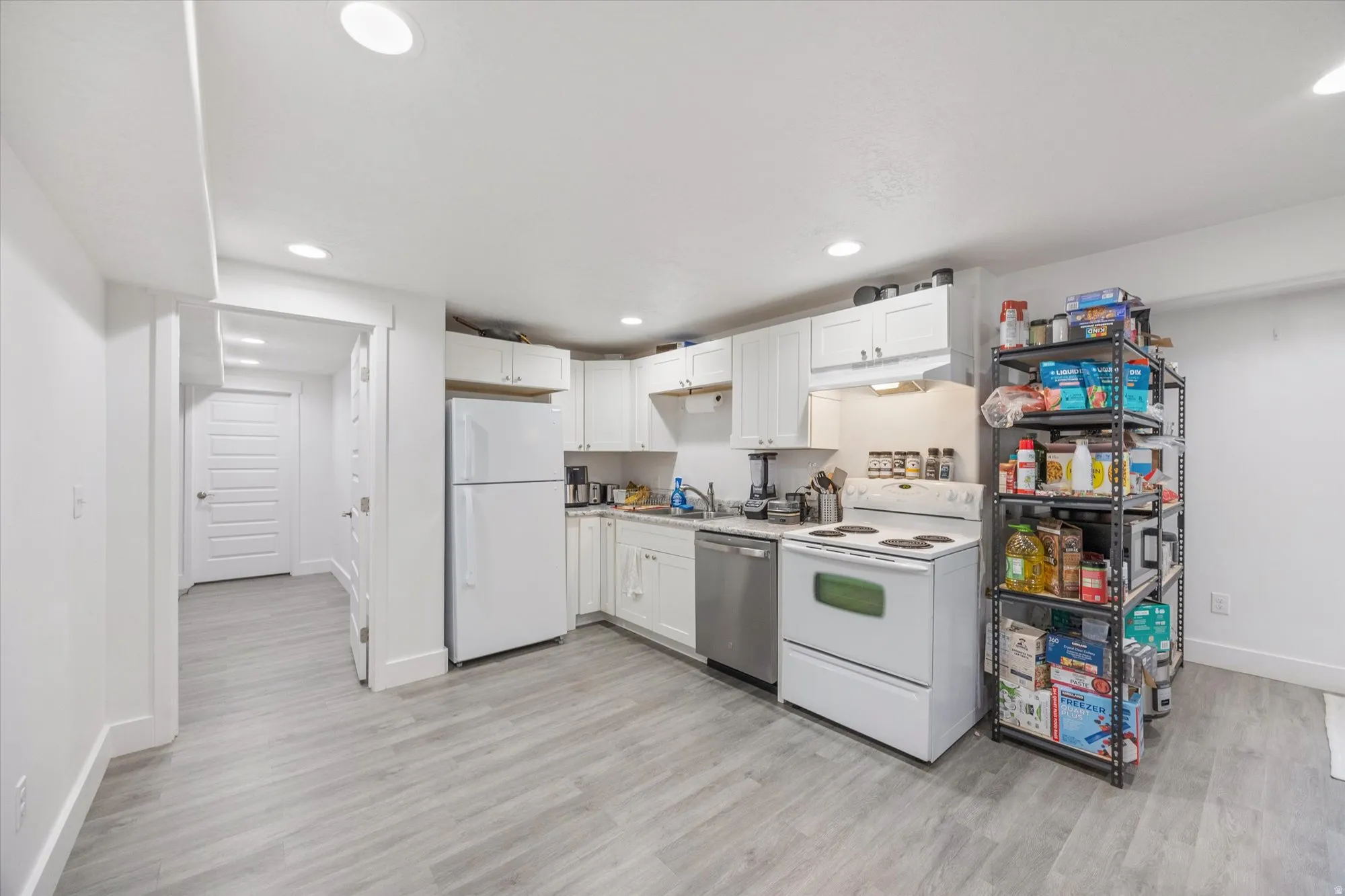 Kitchen featuring white appliances, white cabinetry, light countertops, light wood-style flooring, and recessed lighting