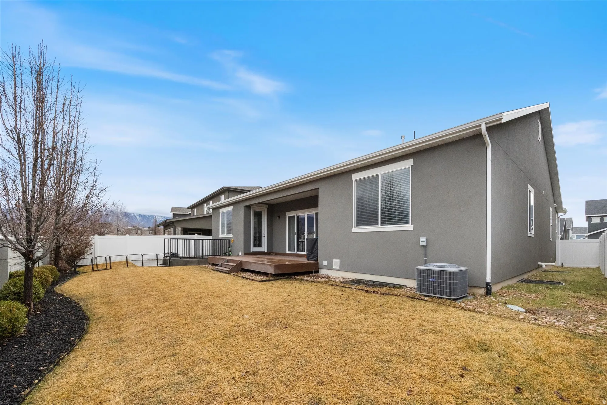 Back of property with a fenced backyard, a wooden deck, and stucco siding