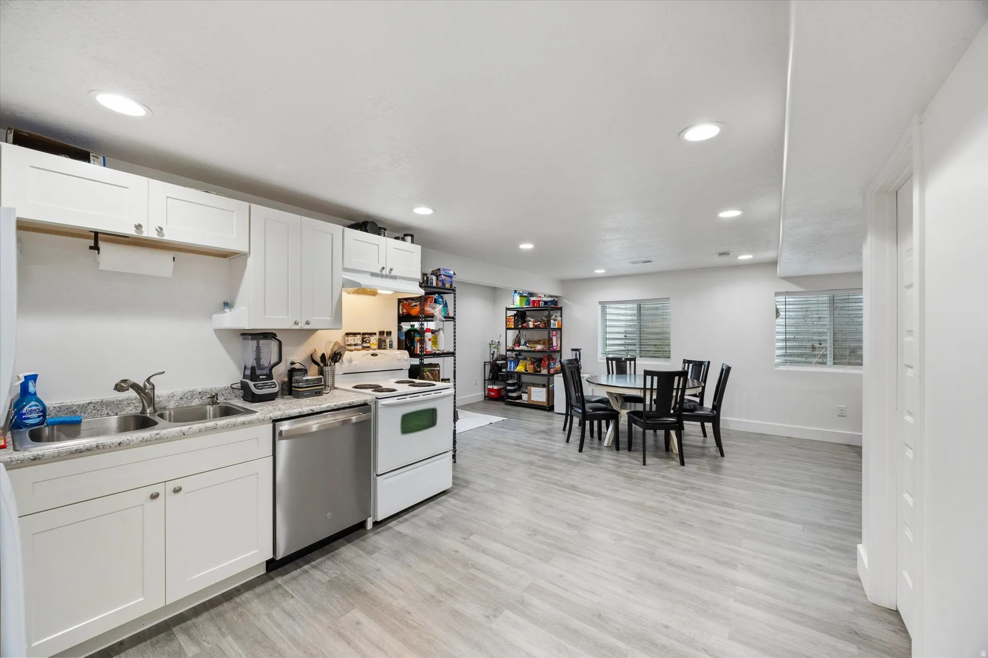 Kitchen featuring light countertops, electric stove, stainless steel dishwasher, light wood-style flooring, and white cabinets