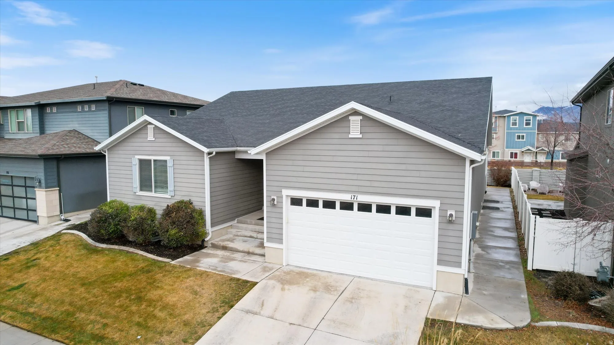Traditional-style house with driveway, roof with shingles, a front lawn, and a garage