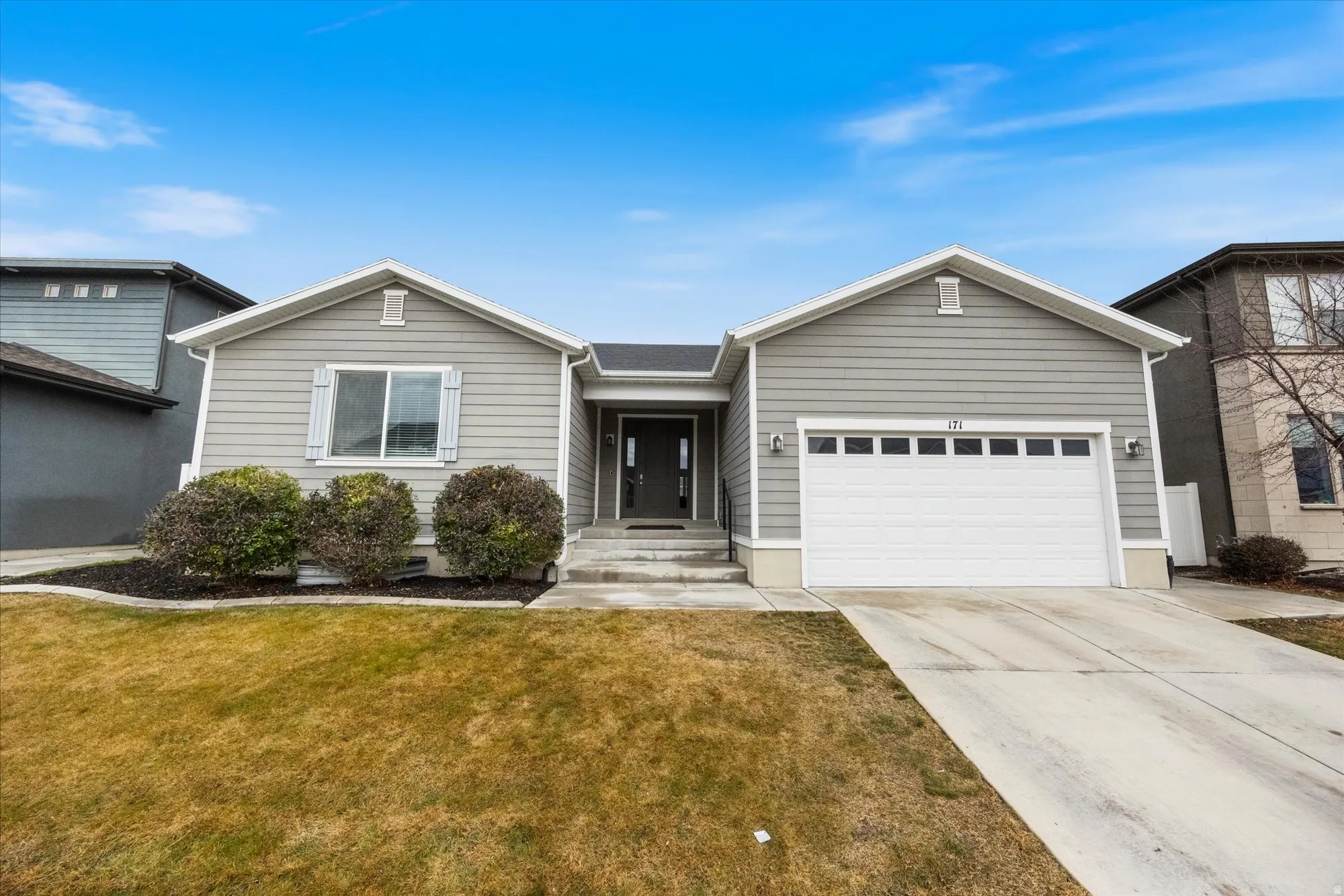 Ranch-style house with a garage, concrete driveway, and a front yard