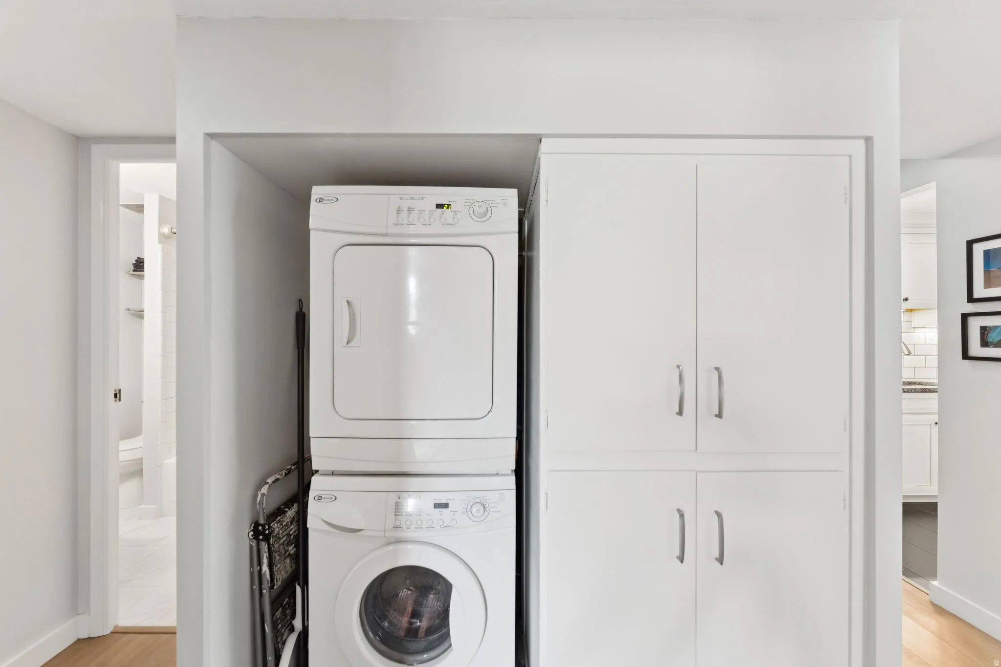 Laundry room with light wood-type flooring and stacked washer and clothes dryer