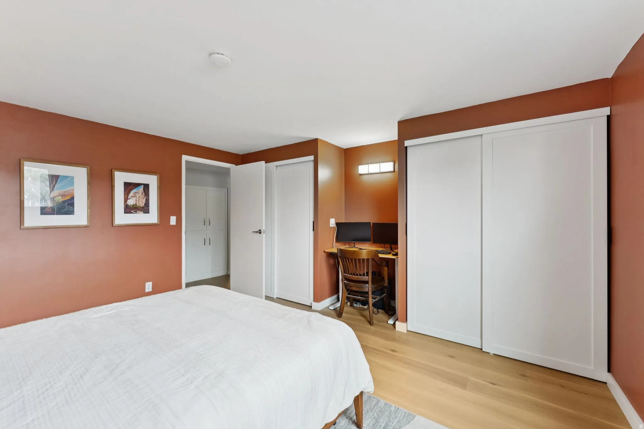 Primary Bedroom with an desk area, light engineered wood flooring, and 2 closets.