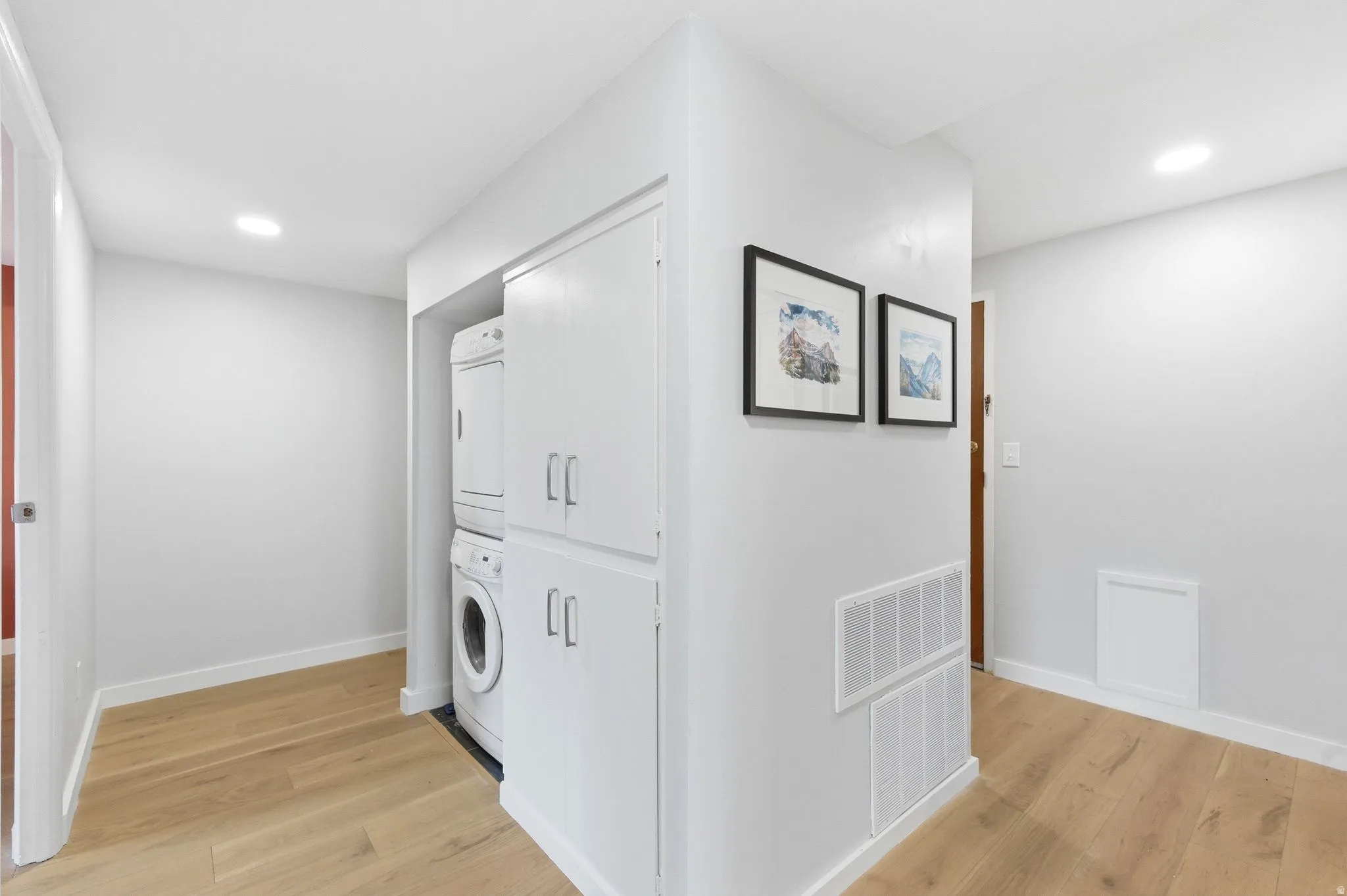 Rare in-unit laundry area featuring recessed lighting, light engineered flooring, and stacked washer / dryer