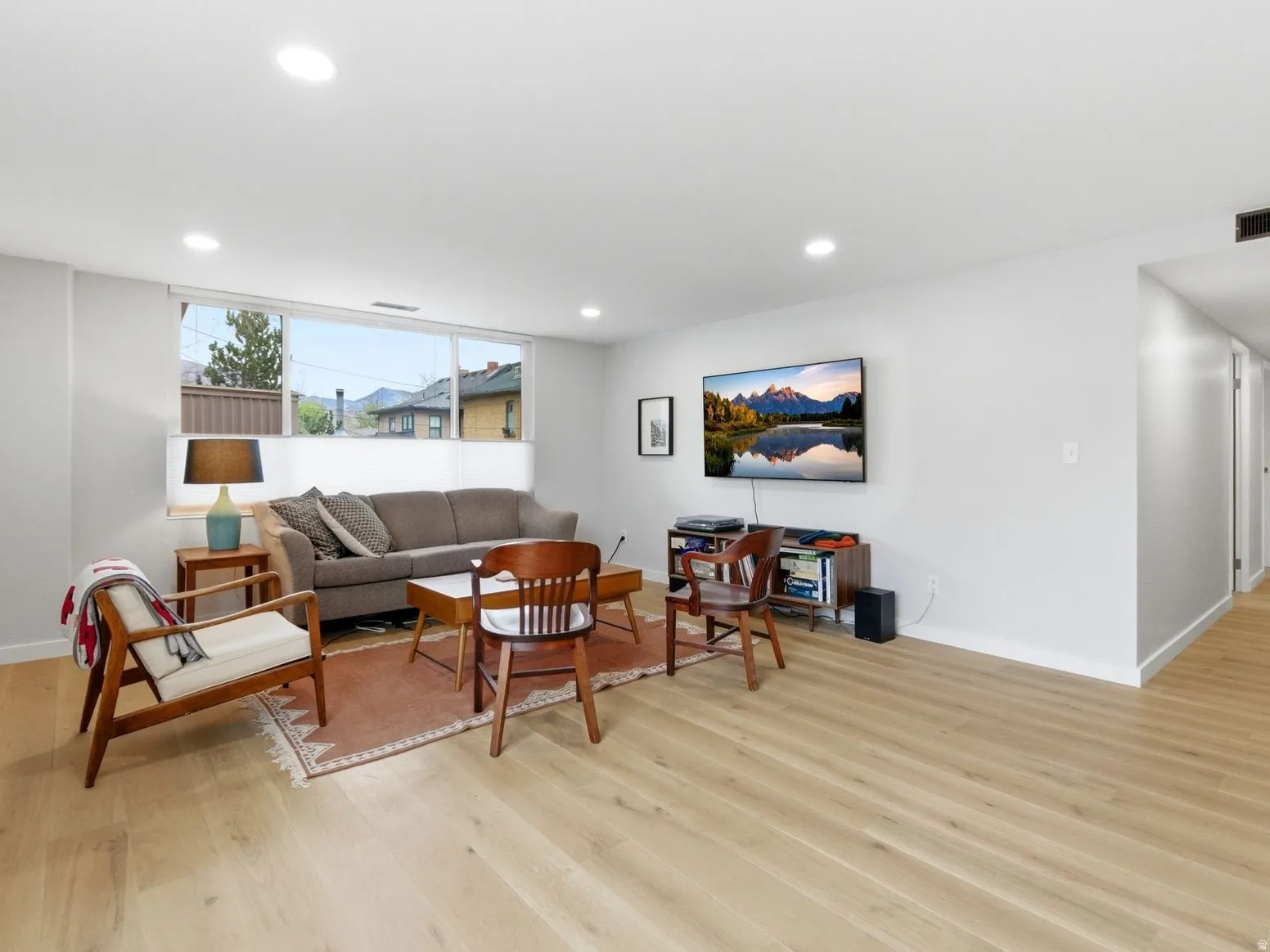 Large living room space with light wood-style flooring and recessed lighting