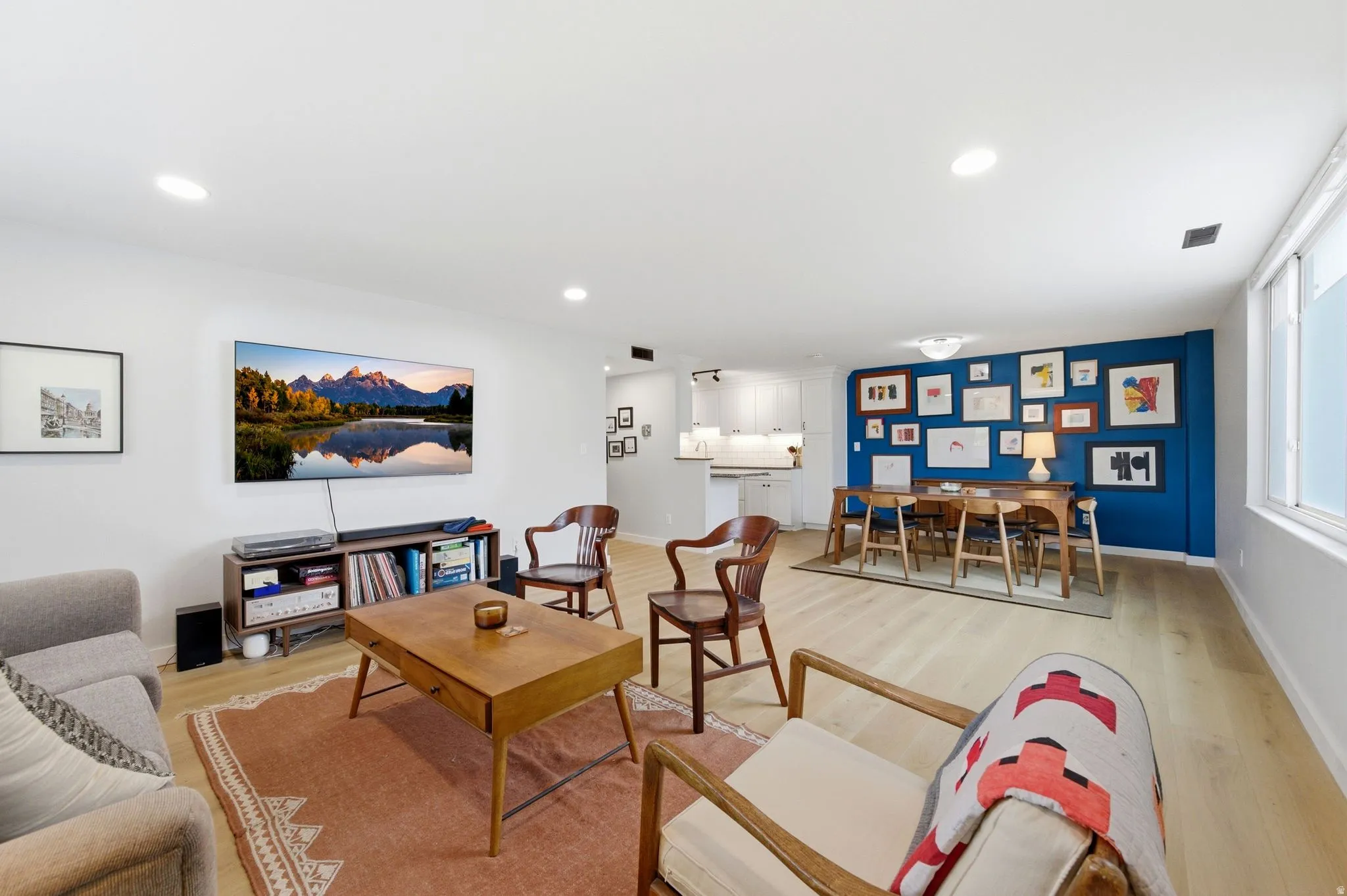 Large open living/dining space area with light engineered wood  floors and recessed lighting