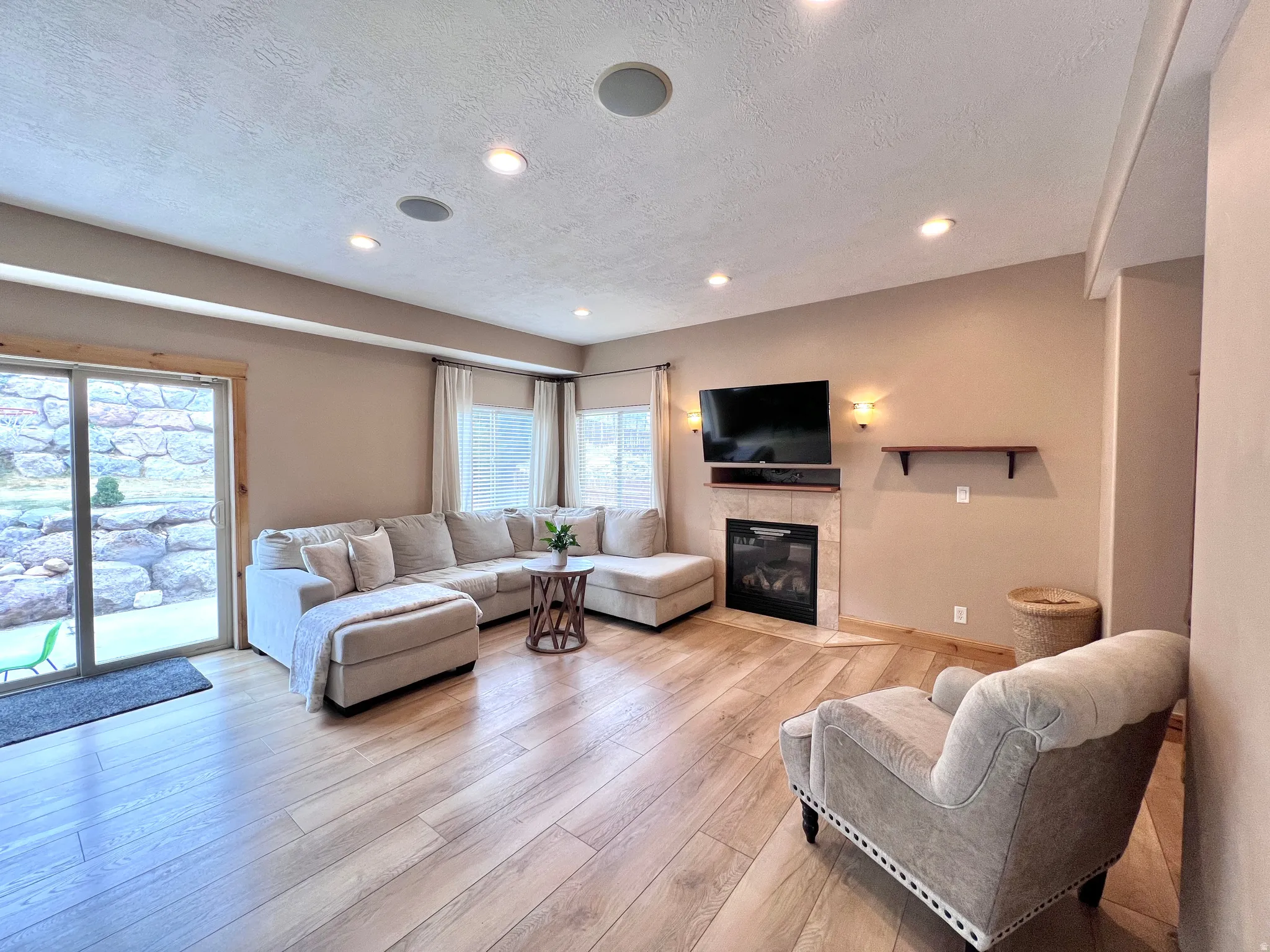 Living area featuring a fireplace, a textured ceiling, light wood finished floors, and recessed lighting