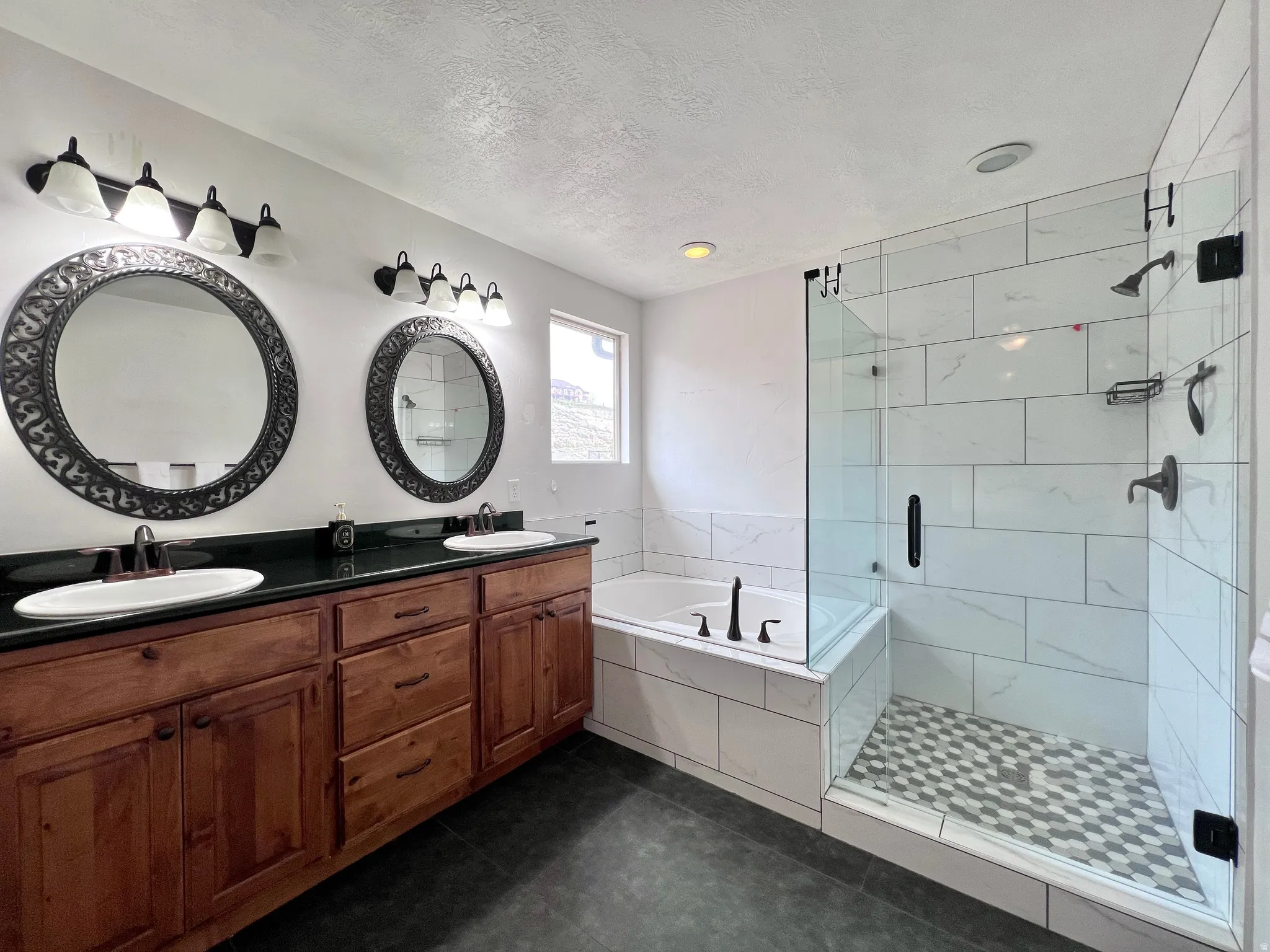 Full bathroom with double vanity, a bath, a stall shower, dark tile patterned floors, and a textured ceiling