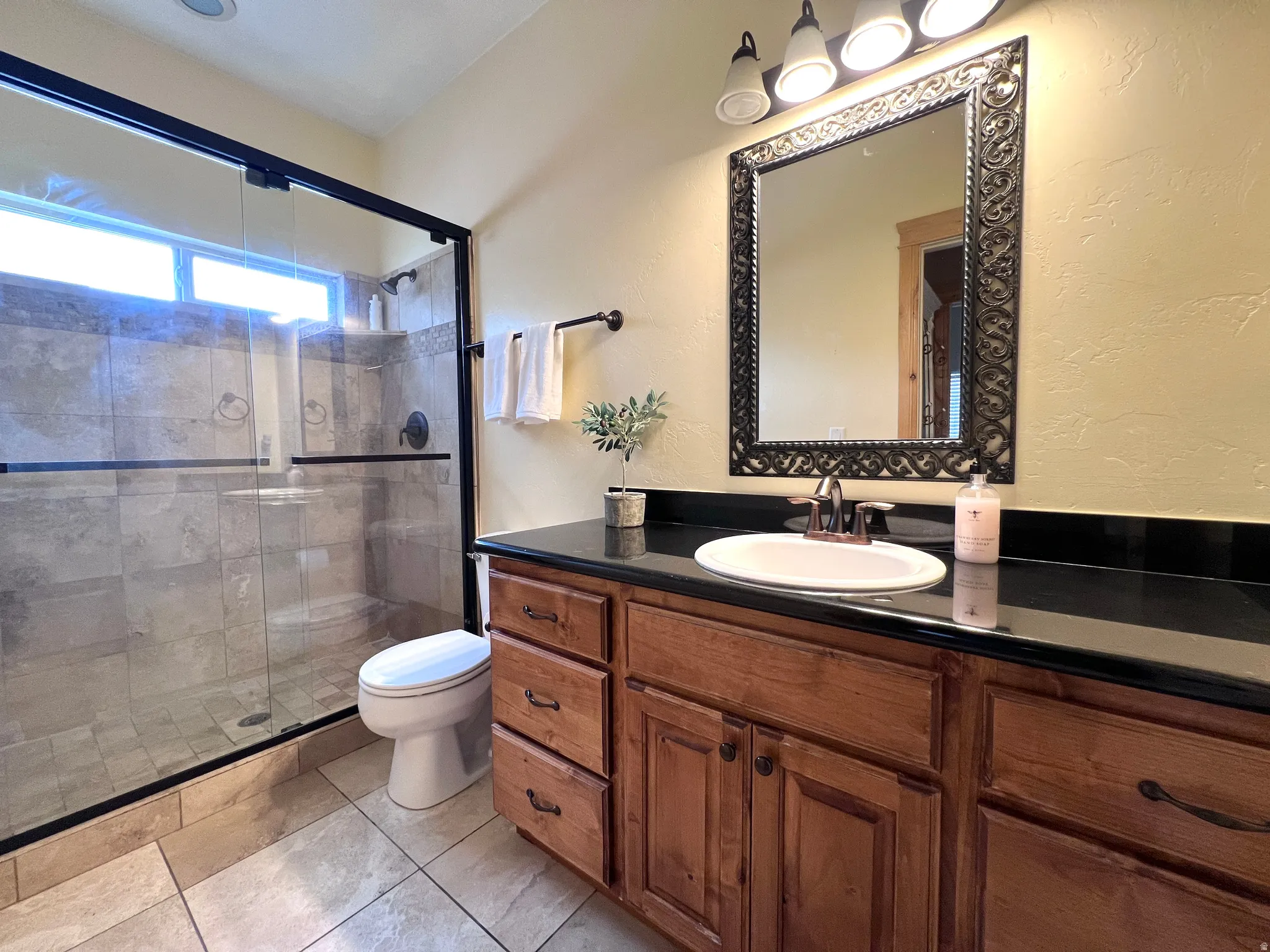 Full bathroom with vanity, a stall shower, a textured wall, and light tile patterned flooring