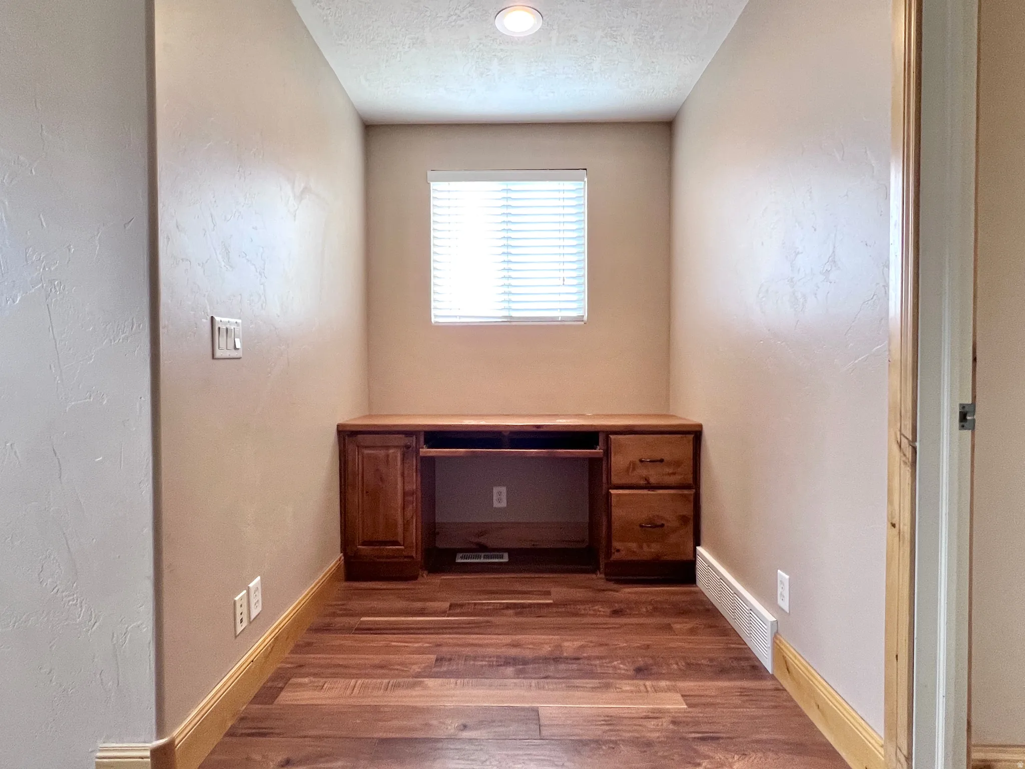Unfurnished office with a textured ceiling, dark wood finished floors, and a textured wall
